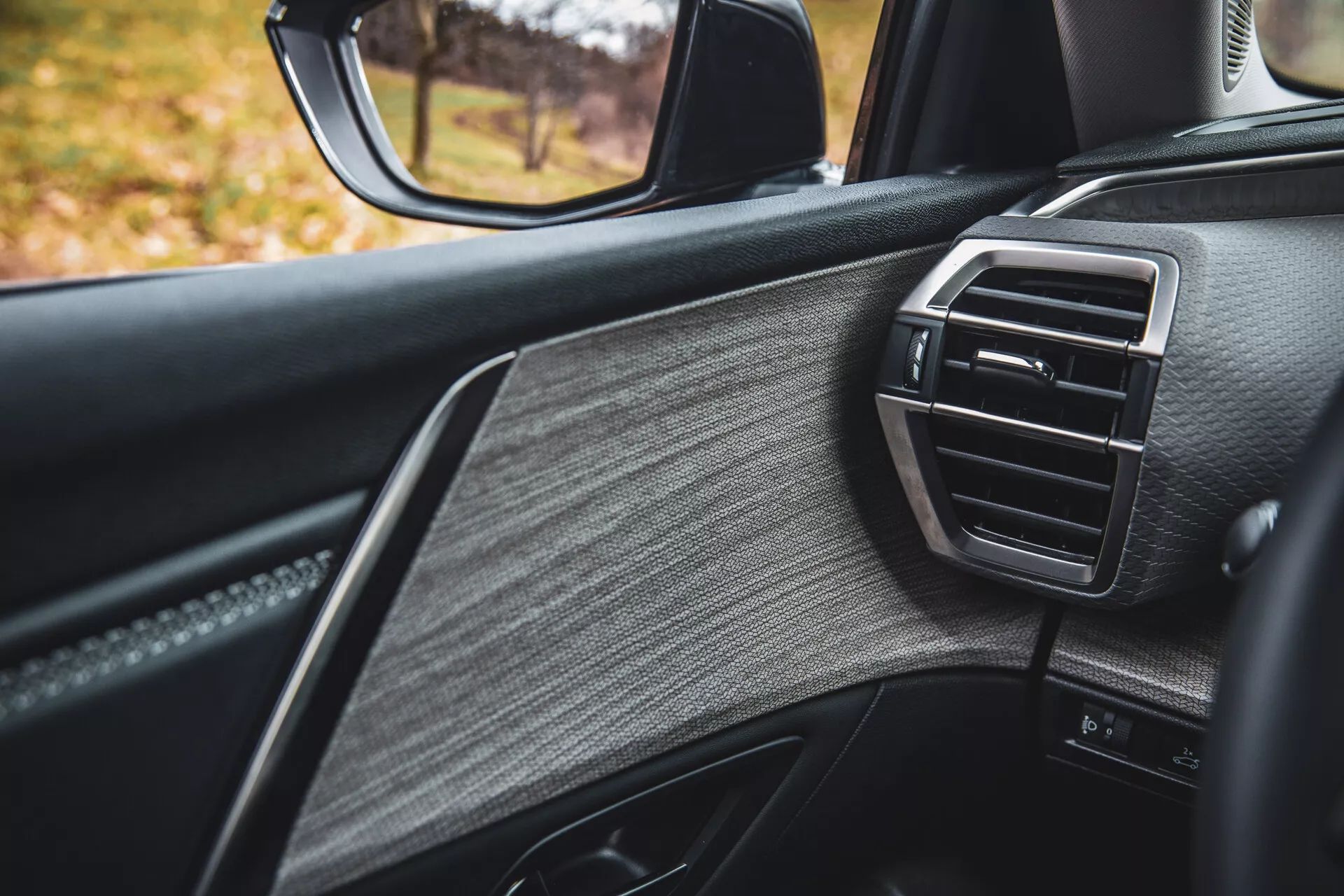 Detaljerad vy över 2022 års Citroen C5-X passagerarsida dörr, som visar lyxig design med texturerat läder, blanka lister och luftventil för klimatkontroll