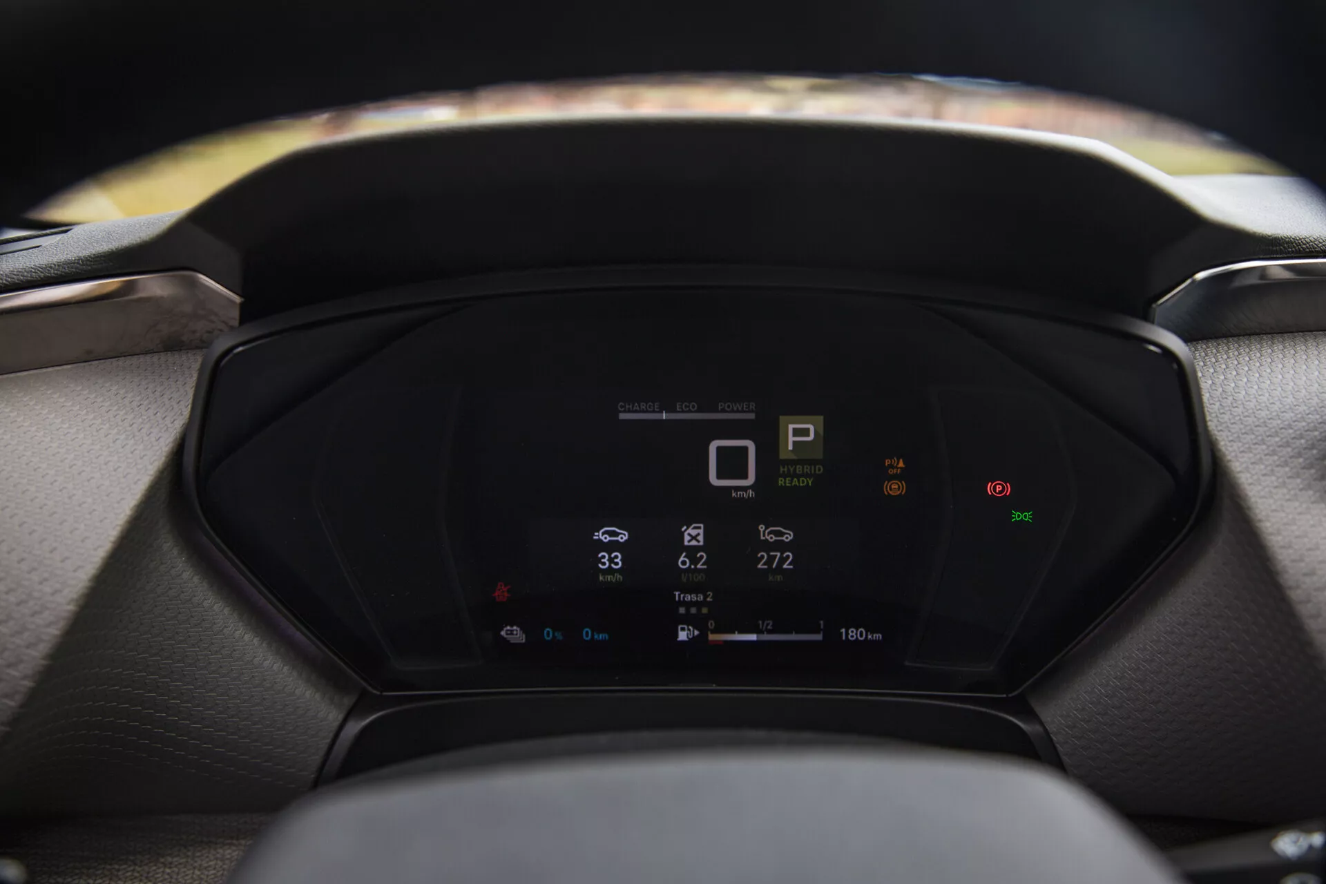 Närbild av en Citroen C5-X 2022 digital instrumentbräda som visar fordonets metrik, inklusive växelindikator, hastighetsmätare och energiförbrukning, med en suddig ratt och vindruta i förgrunden och bakgrunden respektive.