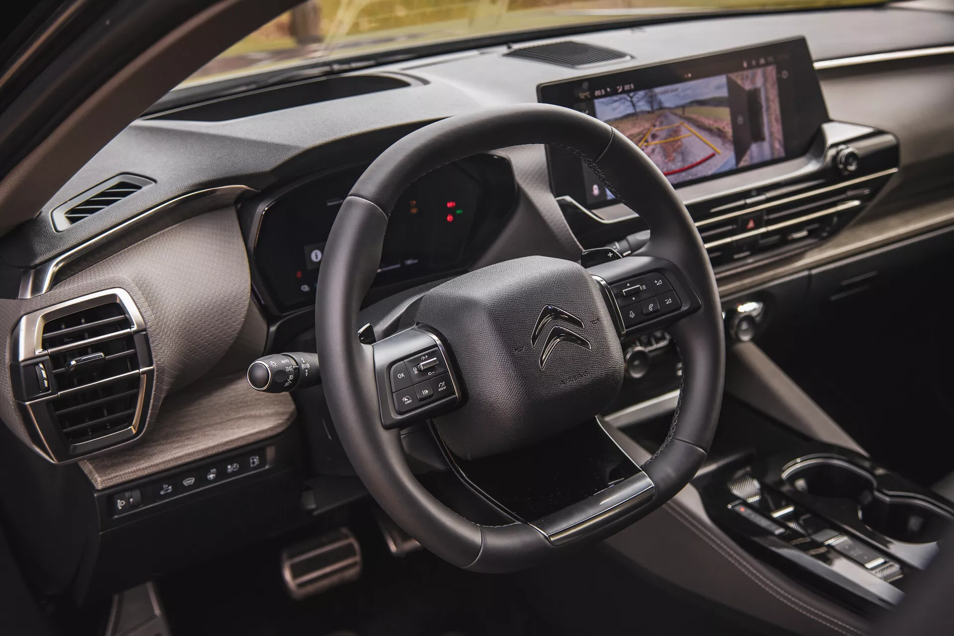 Närbild av interiören i Citroën C5-X 2022 som visar ratten med multifunktionsknappar, en digital instrumentpanel från passagerarens perspektiv och ett pekskärms-underhållningssystem