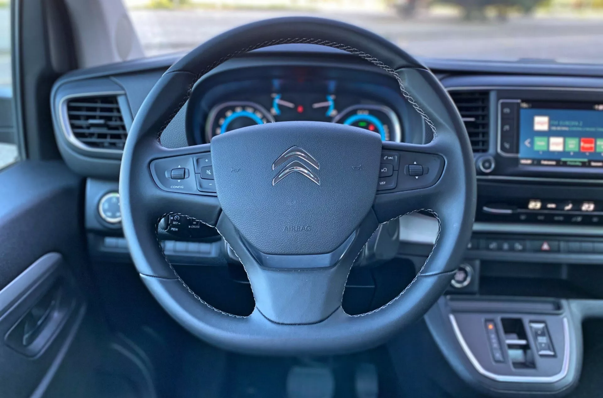 Närbild av interiören i 2016 Citroën Spacetourer med fokus på ratt med multifunktionsknappar, Citroën-logotyp och instrumentbräda inklusive hastighetsmätare, varvräknare och digital display.
