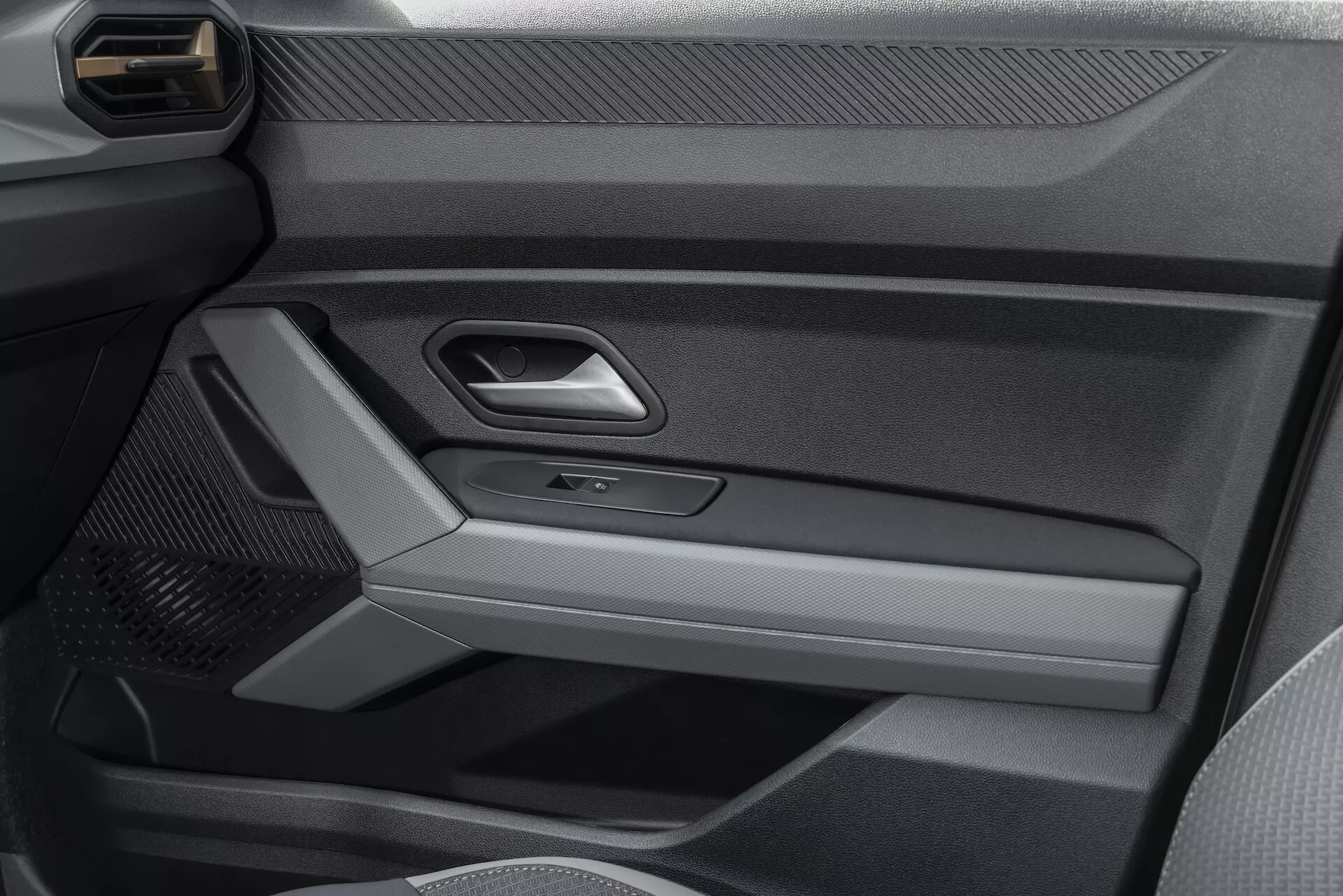 Närbild av innerdörren panelen på Dacia Duster 3:e generationen 2024 som visar en blandning av material med metallisk trim, kraftkontrollknappar och sportiga designfunktioner