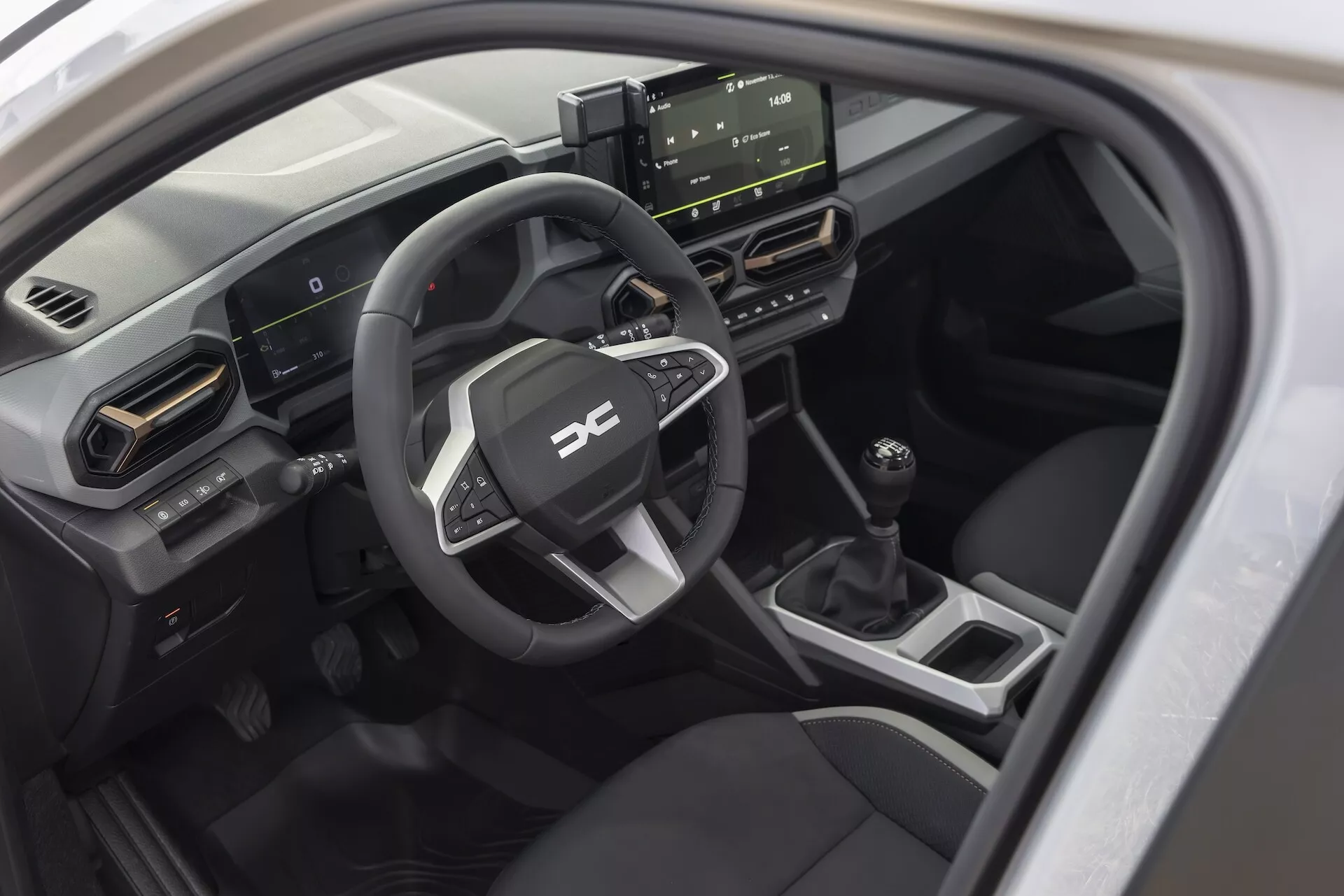 Interiörvy av Dacia Duster 3:e generationen 2024 från passagerarsidan som visar instrumentbrädan, sportratt, digitala instrument, fristående pekskärmsinfotainmentsystem, klimatkontroll och manuell växellåda