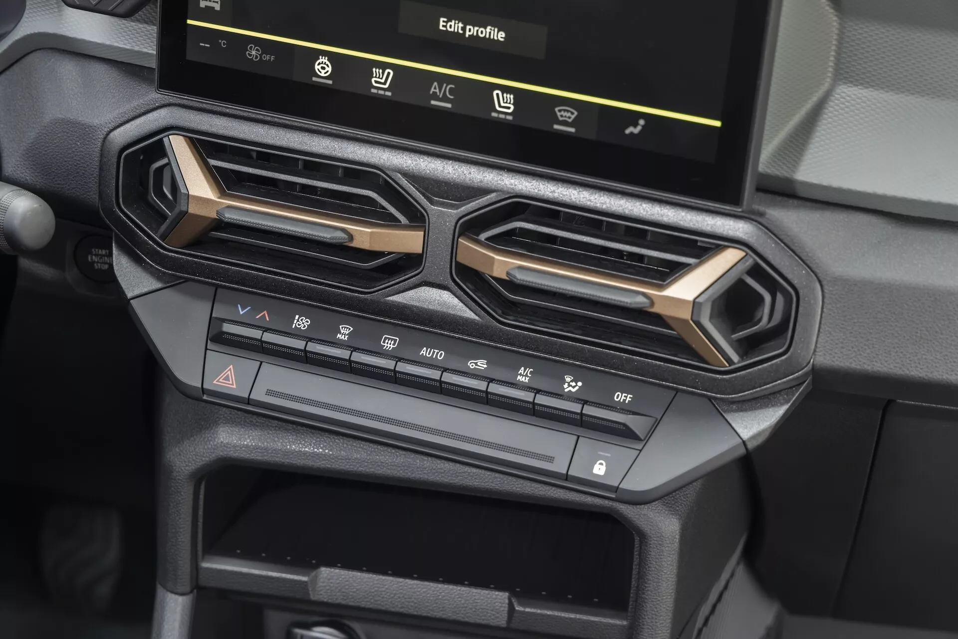 Interiörbild av Dacia Duster 3:e generationen 2024 som visar central konsol med avancerade luftkonditioneringskontroller och infotainment pekskärm med profilval, med moderna geometriska luftventiler och praktiska designelement