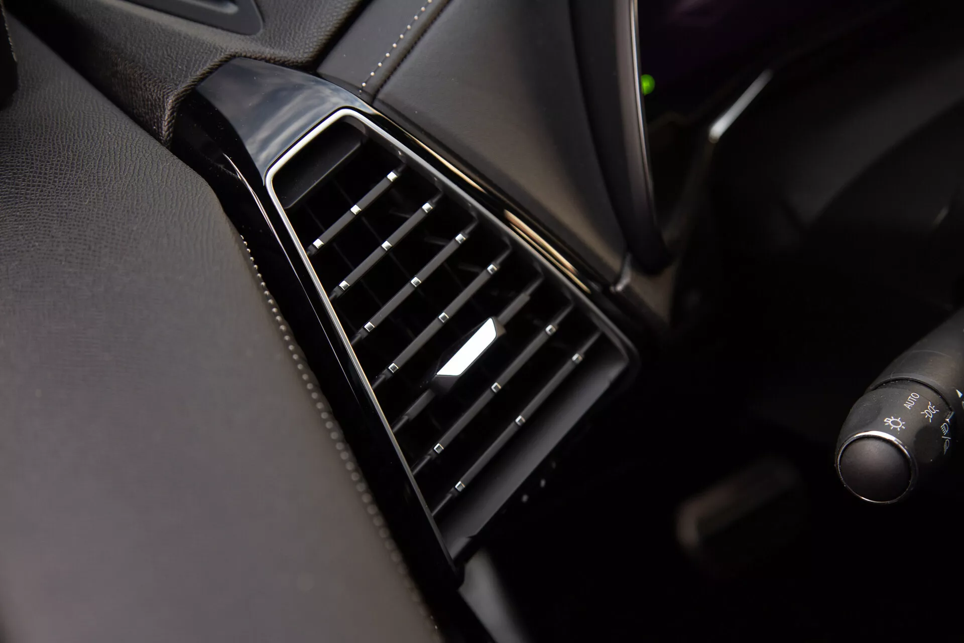 Närbild av luftventilen på DS Automobiles DS-7 2022 instrumentbrädan med vertikalt justerbara svarta lameller, glänsande bezel och en silveraccent på kontrollen, som visar fordonets interiördesignkvalitet och material