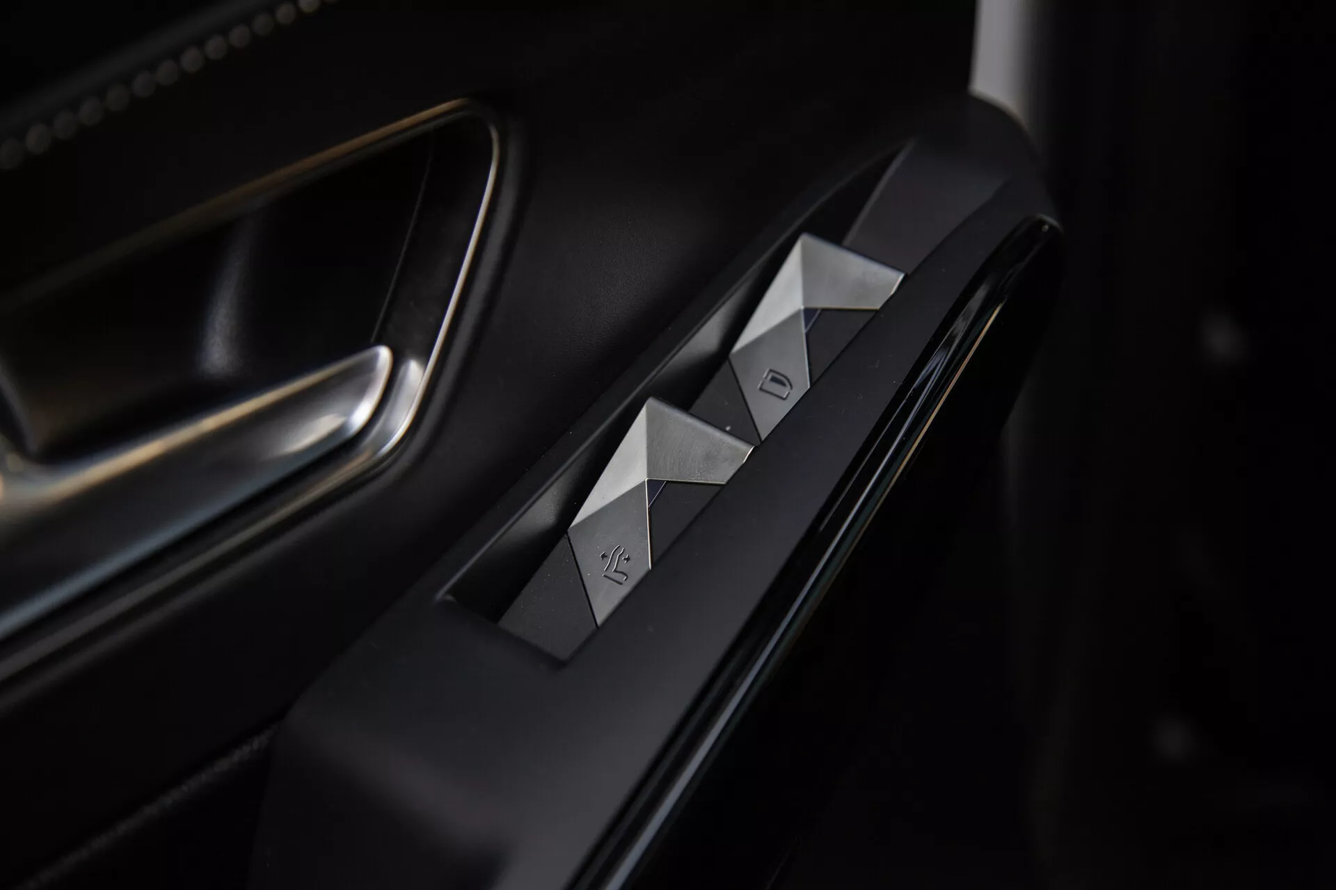 Närbild av förarsidans dörrkontroller i DS Automobiles DS-7 2022, med diamanthuggna fönsterbrytare, dörrlåsknapp, premium matta och metalliska ytor samt sofistikerad belysning som framhäver den ergonomiska designen.