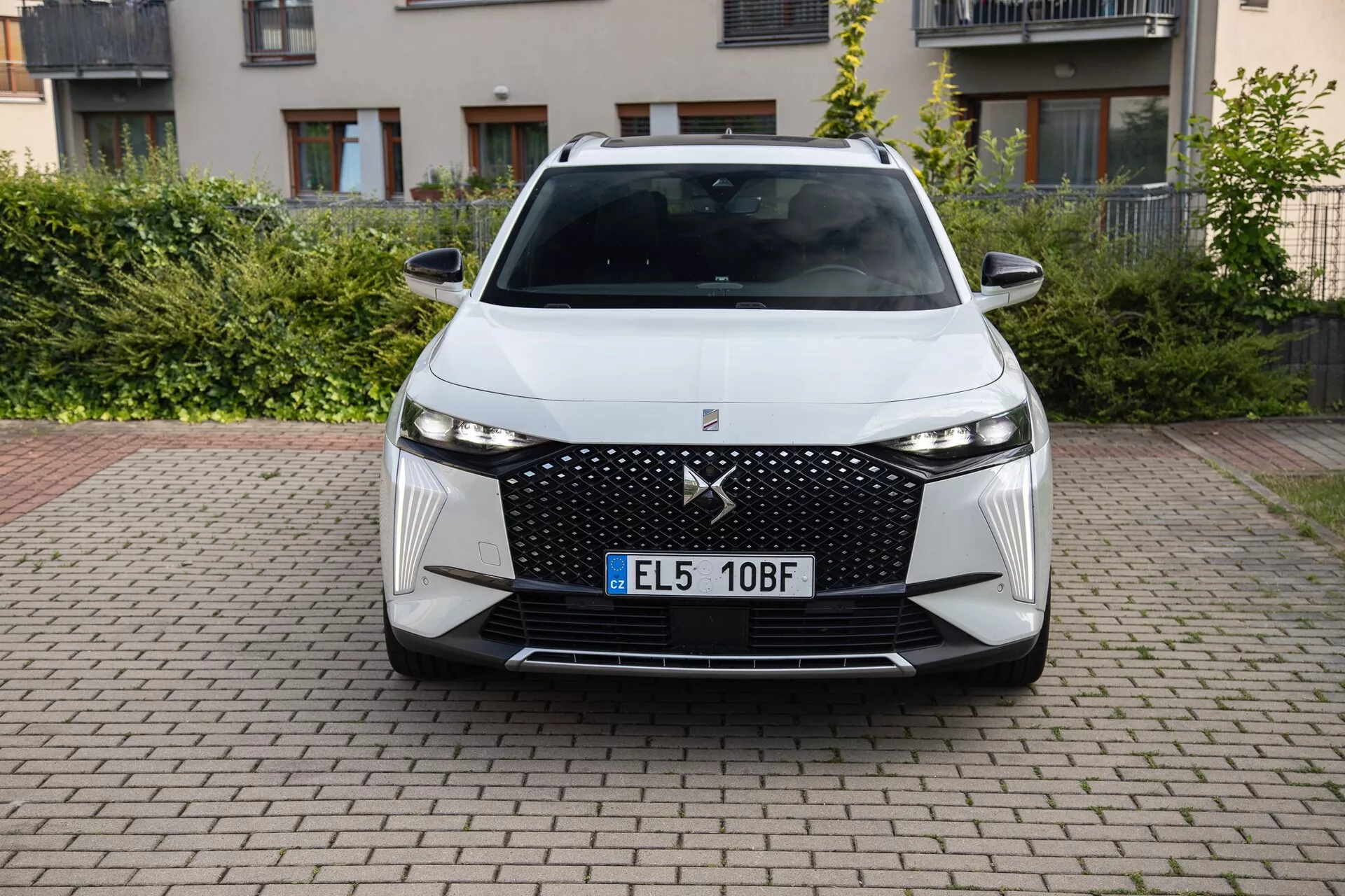 Frontvy av DS Automobiles DS-7 2022 som visar upp sin moderna design, med en stor grill med diamantmönster, smala LED-strålkastare, vinklade luftintag och avancerade förarassistanssystem