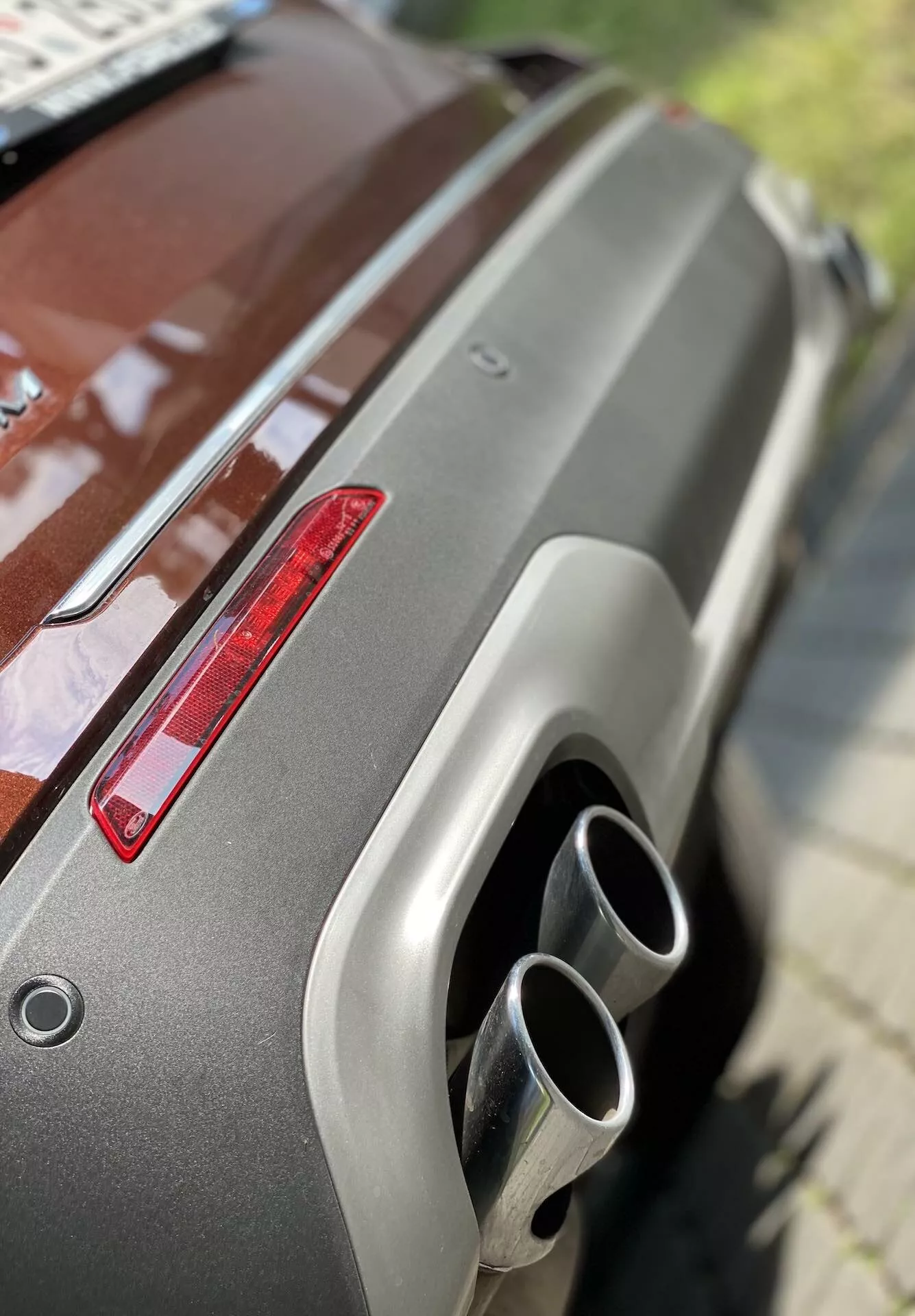 Närbild av den bakre delen på en Ford Explorer 2019, som visar metallfärgen, bakspoilern, det röda bakljuset och de dubbla kromavgasrören. Den snedställda vinkeln från en upphöjd position framhäver den välskötta ytan och moderna designelement.