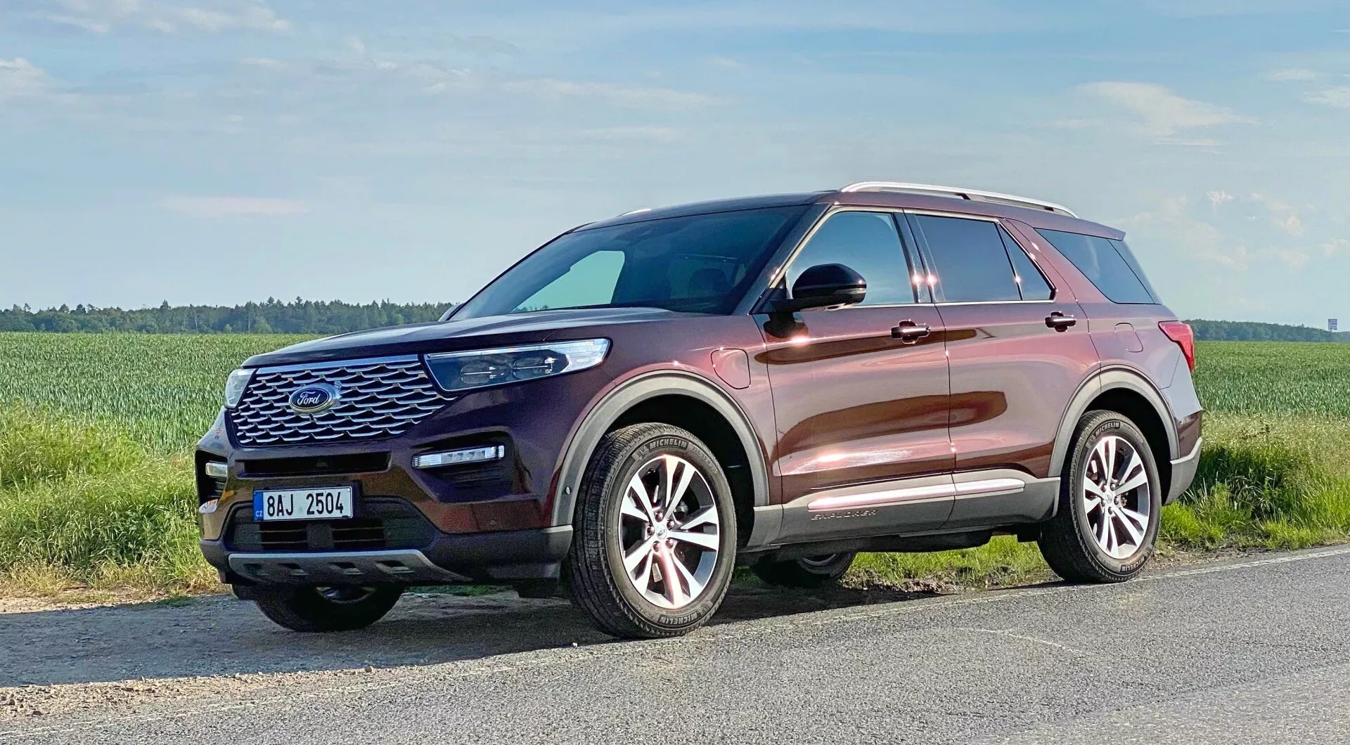 2019 Ford Explorer - En modern SUV fångad från en trekvarts frontal vy, som framhäver dess främre grill med hexagonalt mönster och stort emblem, formad motorhuv, eleganta LED-strålkastare, dimljus, luftintagsventiler, fler-eker lättmetallfälgar, något uppåtgående fönsterlinje, takräcken, sidospeglar med integrerade blinkers och metallickarossfärg som speglar en högkvalitativ finish.