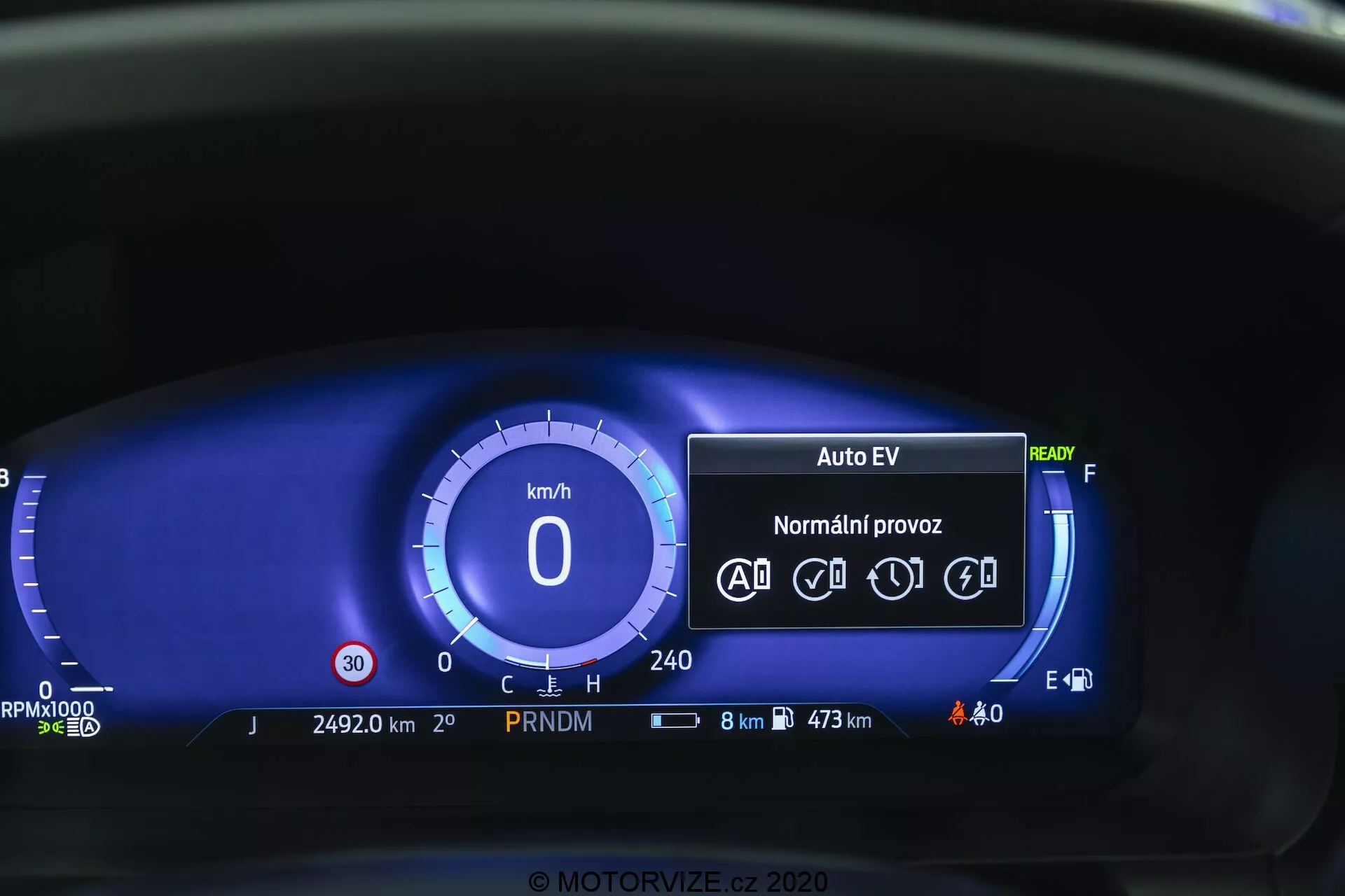 Närbild av den digitala instrumentpanelen i Ford Explorer 2019 ur förarens perspektiv. Den digitala hastighetsmätaren visar 0 km/h, och instrumentpanelen inkluderar läget 'Auto EV', vilket indikerar ett elektriskt eller hybrid system, status 'Redo', ikoner för automatiska körfunktioner, vägmätare på 24 920 km, PRNDM växelindikator, statusikoner för batteri och utvändiga ljus, bränsleekonomidisplay med 8 km kvarvarande och maximal räckvidd på 473 km, digital bränslemätare och inga varningslampor. Den blå färgschemat erbjuder en modern estetik.