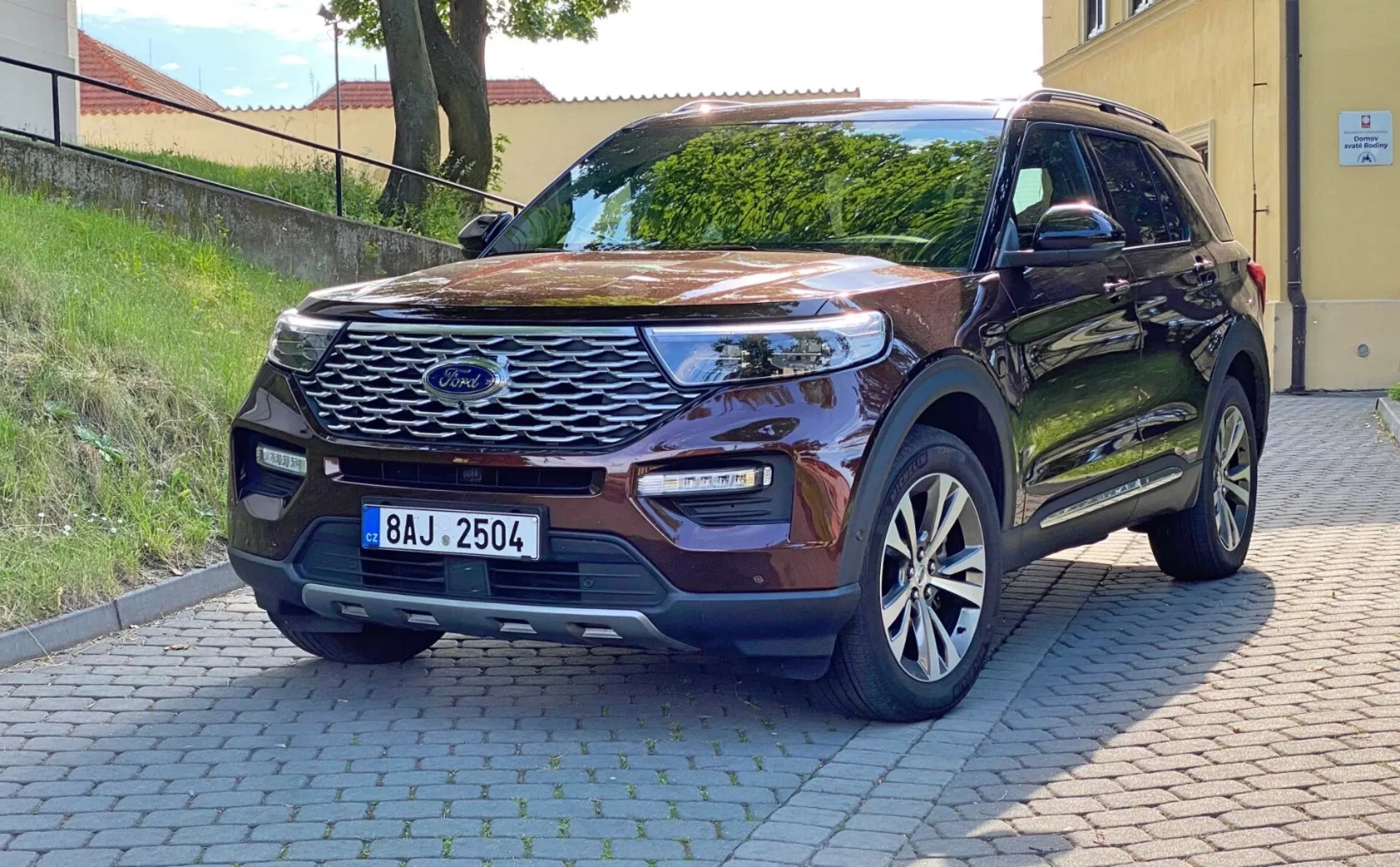 Bild på en modern 2019 Ford Explorer SUV parkerad på en asfalterad yta, tagen från en trekvart frontperspektiv. Visar den framträdande nätfrontgrillen med ett centralt emblem, eleganta LED-strålkastare, dimljus integrerade i stötfångaren, parkeringssensorer, skulpterad motorhuv, lättmetallfälgar, sidospeglar i karossfärg med blinkers, design för nyckelfri åtkomst och en bostadsbakgrund. Naturligt dagsljus som framhäver dess yttre egenskaper och teknologiska framsteg.