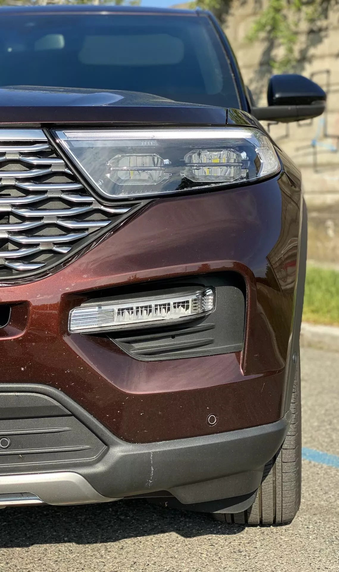 Närbild av vänster framkvartal på en modern märklila 2019 Ford Explorer, med intrikat kromgrill, elegant LED-strålkastare med dagsljus, kromaccentuerad dimljushölje och metallisk lack som gnistrar i solljuset.