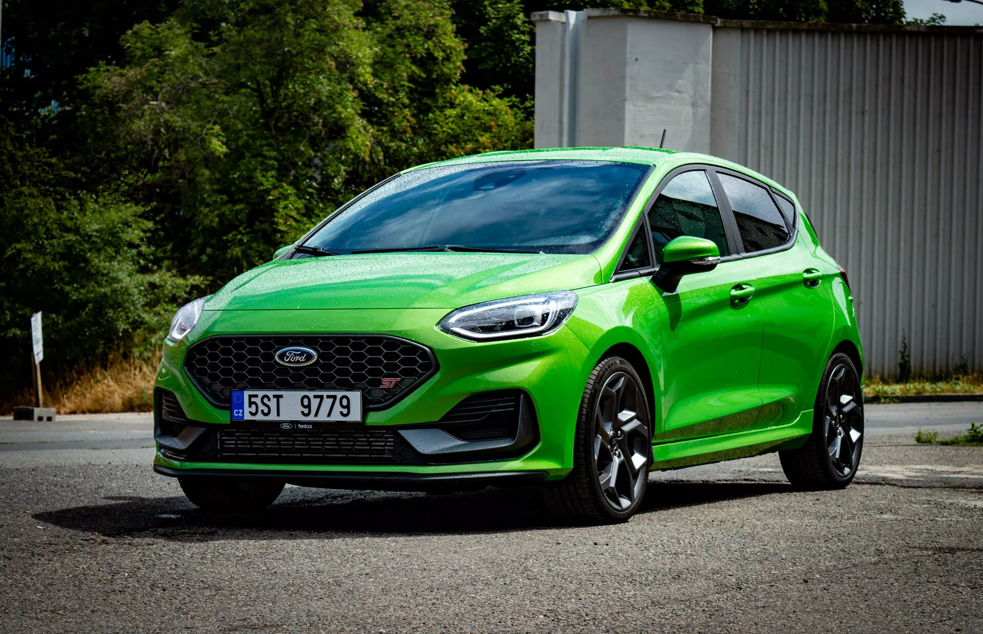 2022 vibrerande grön Ford Fiesta hatchback i en tre fjärdedels främre vy som visar främre grillen med emblem, sportig stötfångare med dimljus, vassa vinklade strålkastare, aerodynamiska konturer, stora svarta legeringshjul och ett modernt belysningssystem