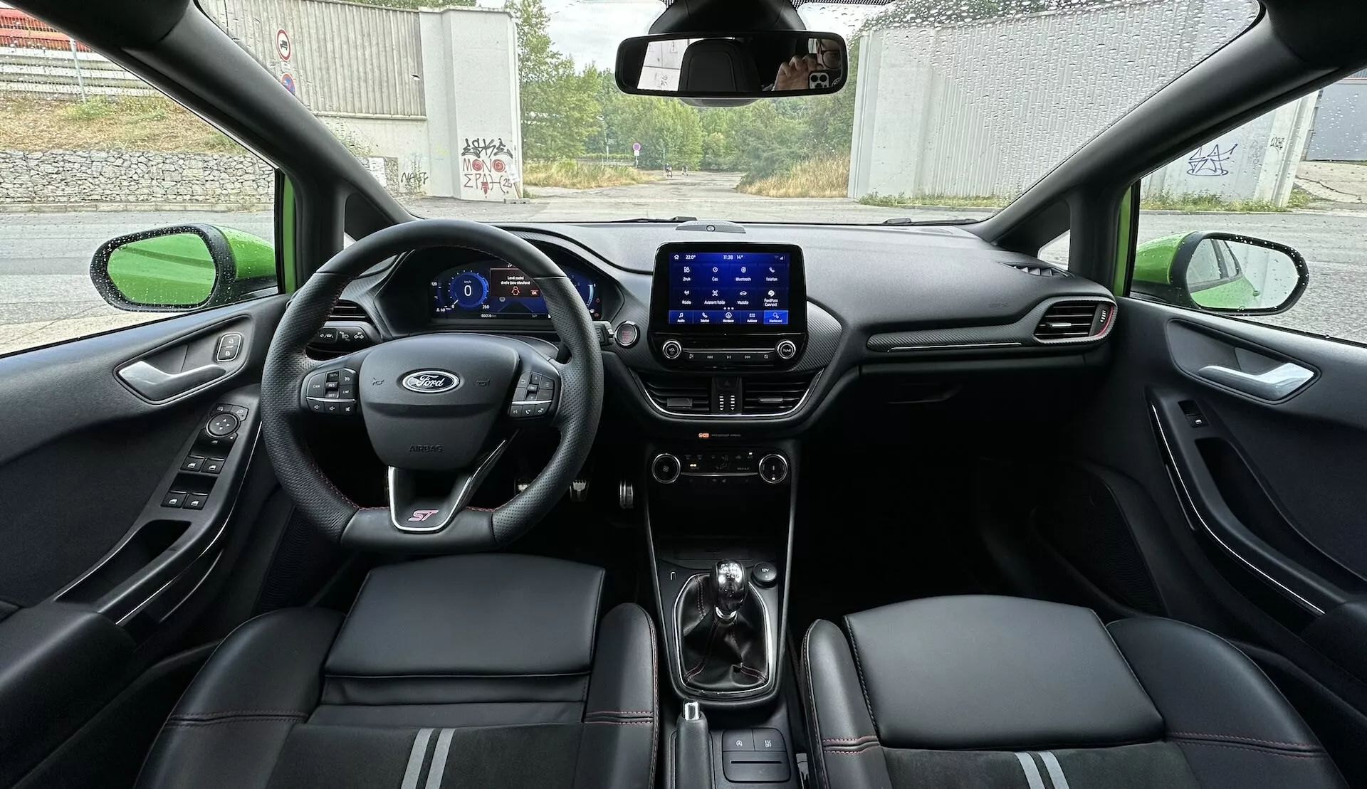 Interiör vy av Ford Fiesta 2022 från baksätet, visar hela cockpit med digital instrumentbräda, multifunktionsratt och lädersäten med stygnaccents