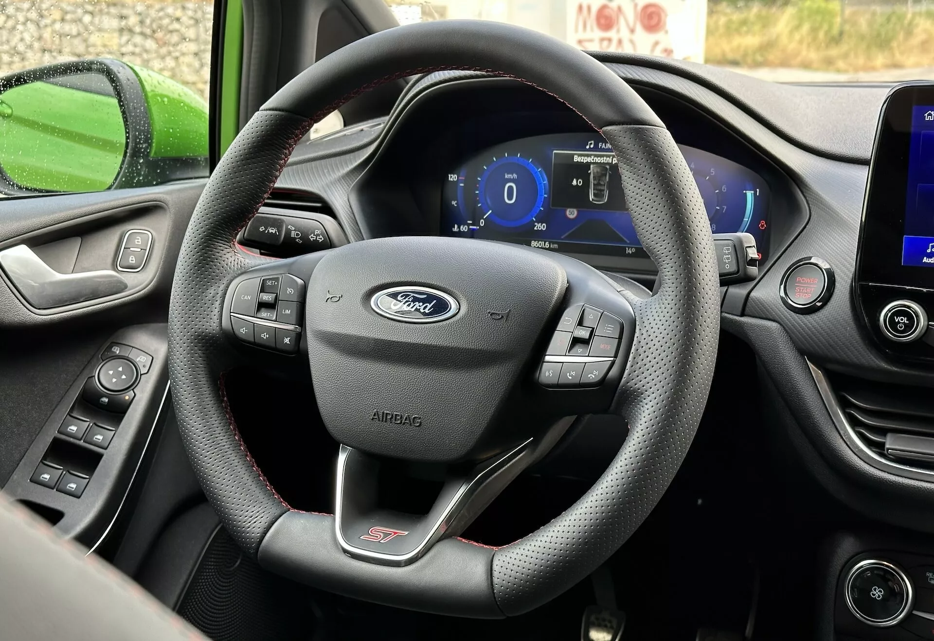 Interiörvy av Ford Fiesta 2022 fokuserad på läderinbunden trespakig ratt med multifunktionskontroller och digital instrumentpanel från förarsätets perspektiv