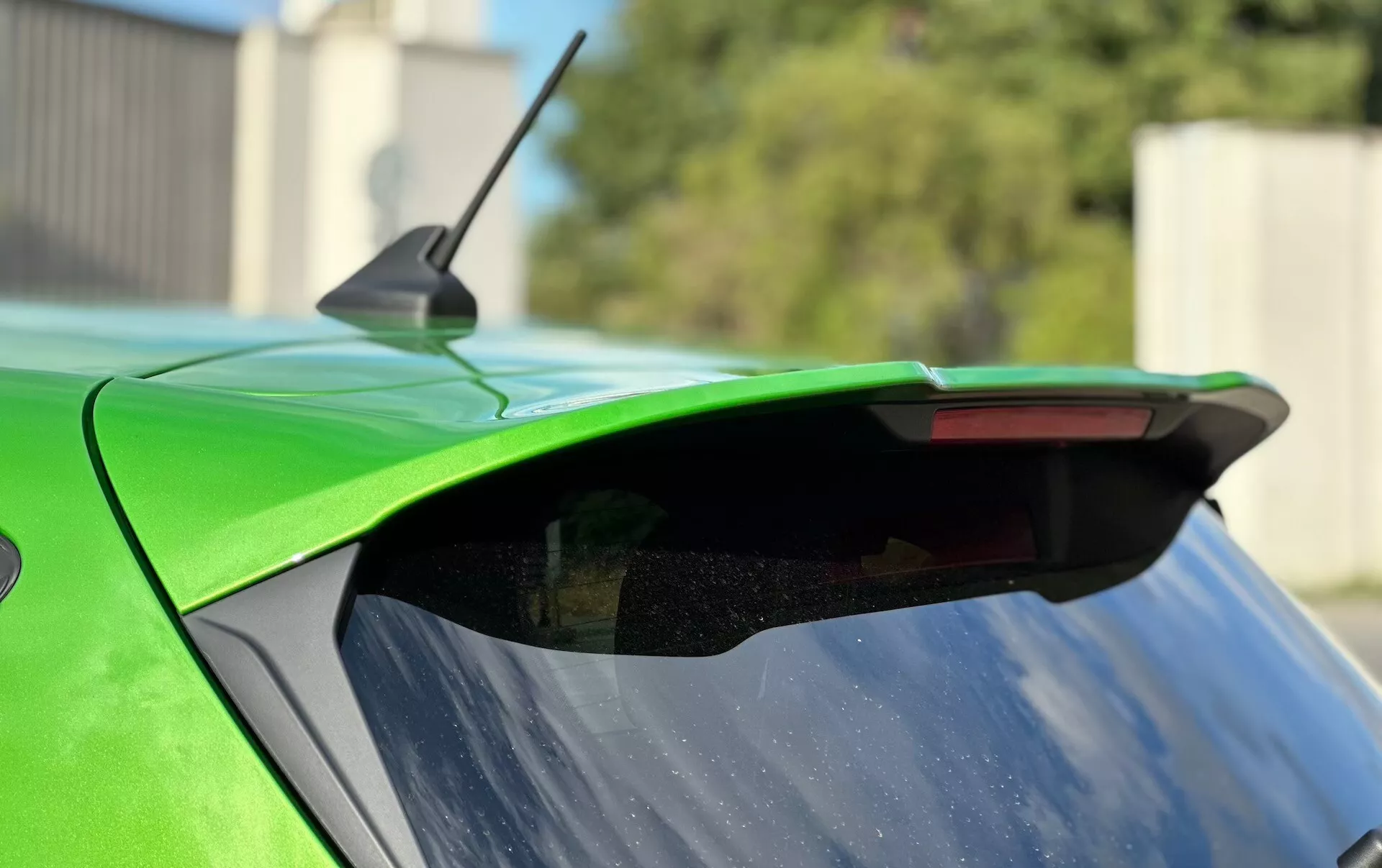 Närbild av bakändan på en Ford Fiesta 2022 som framhäver eftermarknadsspoilern, livlig grön färg och integrerat tredje bromsljus