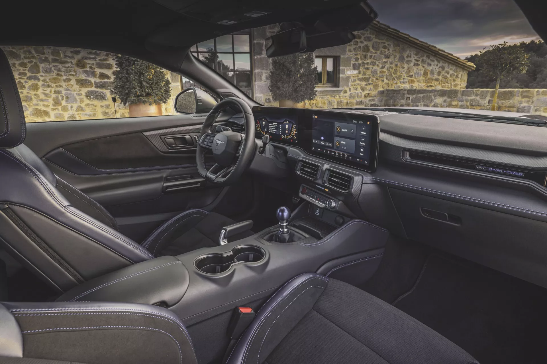Interiörvy av Ford Mustang 2:a generationen 2024 från baksätet, som visar instrumentbrädan, widescreen-infotainmentsystem, sportstolar och avancerade komfortfunktioner