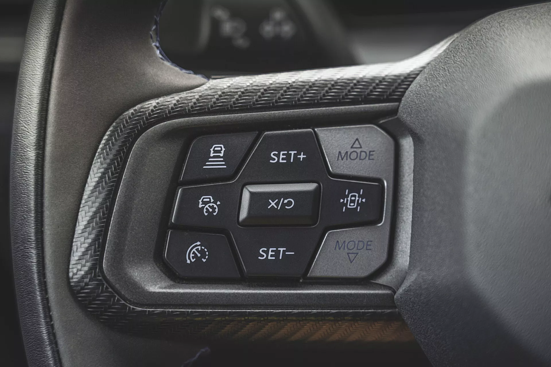 Närbild av kontrollerna på ratten till Ford Mustang 2024 av den andra generationen som belyser adaptiv farthållare, filhållningsassistans och knappar för displaylägen på instrumentbrädan, sedd från förarsätets perspektiv