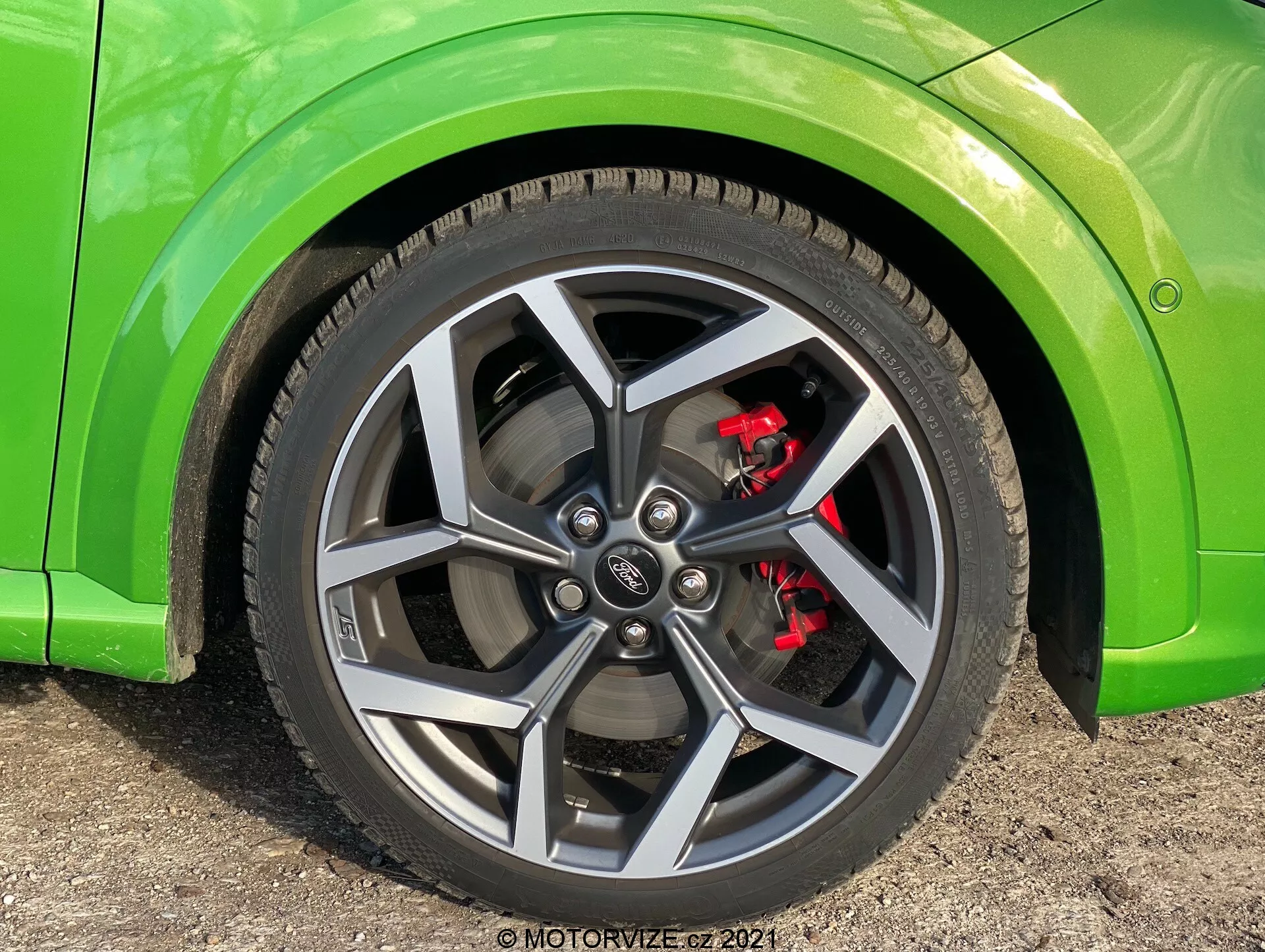Närbild av ett Ford Puma 2020 hjul med flerspetsig mörkgrå design, röd bromsok, prestanda lågprofil däck och limegrön kaross, tagen från låg vinkel som visar hjulet nästan rakt fram med lätt synlighet av bilens sida.