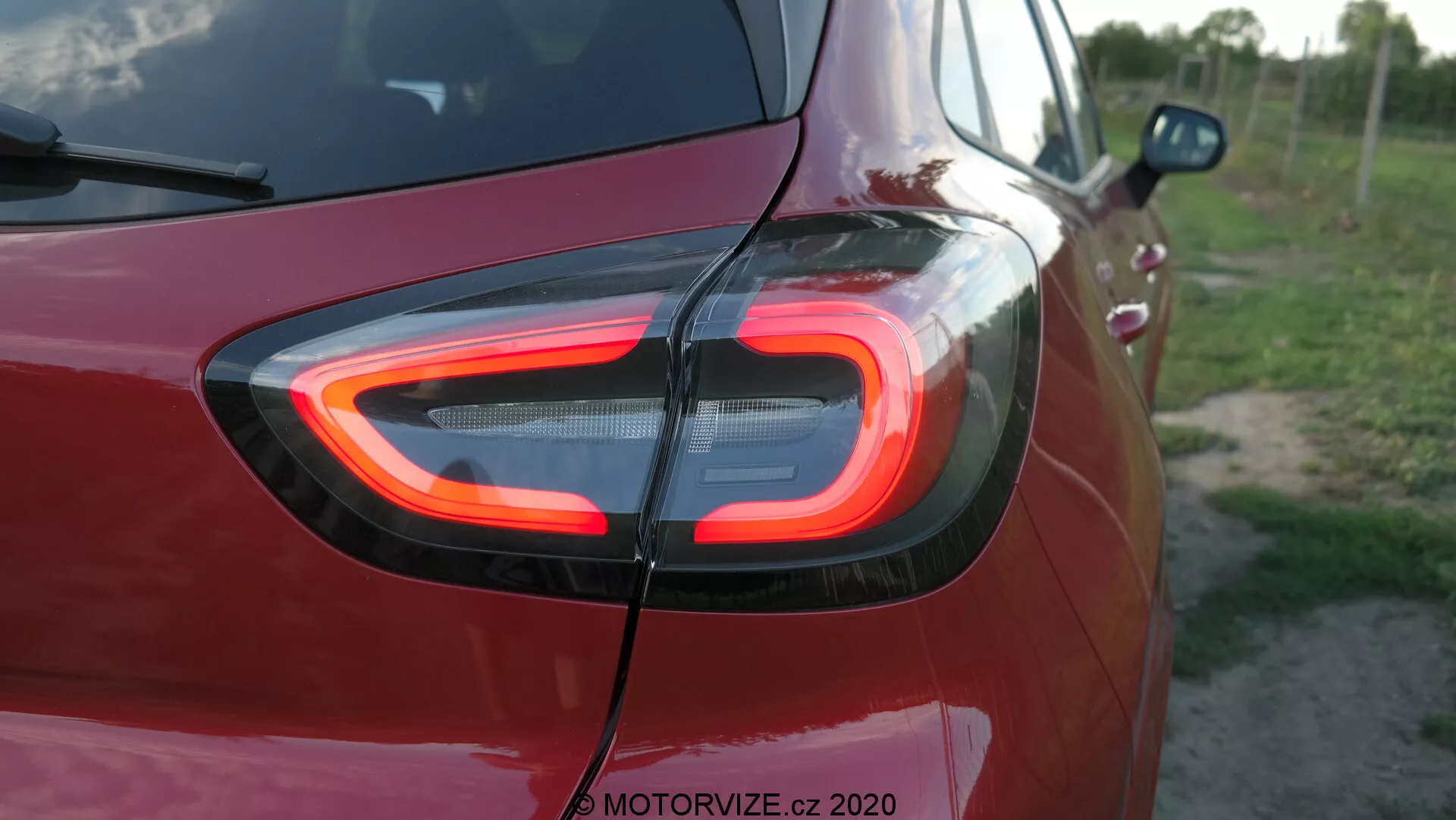 Detaljerad närbild av bakre delen av en Ford Puma 2020, med det karakteristiska C-formade LED-bakljuset upplyst. Fotot är taget från en bakre trekvartsvinkel vilket framhäver den avancerade belysningstekniken och moderna designen, med vattenstämpeln 'MOTORVIZE.cz 2020' som anger källan.