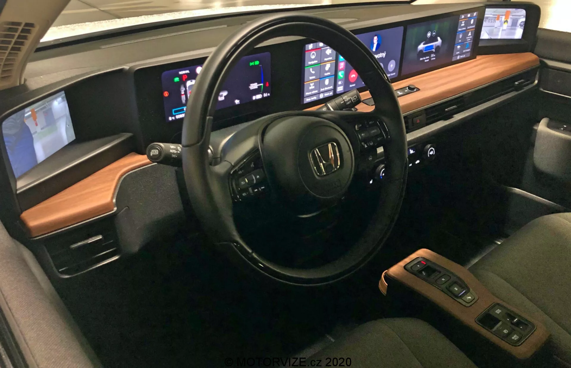 Interiören i Honda e 2020 som visar avancerade funktioner inklusive multifunktionell ratt med ljud- och röstkontroller, digital instrumentbräda som visar hastighet och bränslenivå, central infotainmentsystem kompatibelt med Apple CarPlay och Android Auto, automatisk klimatanläggning med dubbelzon, bekväma säten med lädermaterial och uppvärmning, central konsol med växelspak och förvaring, avancerade förarassistanssystem, anslutningsalternativ som USB-portar och trådlös laddning, premium ljudsystem och anpassningsbar ambient belysning.