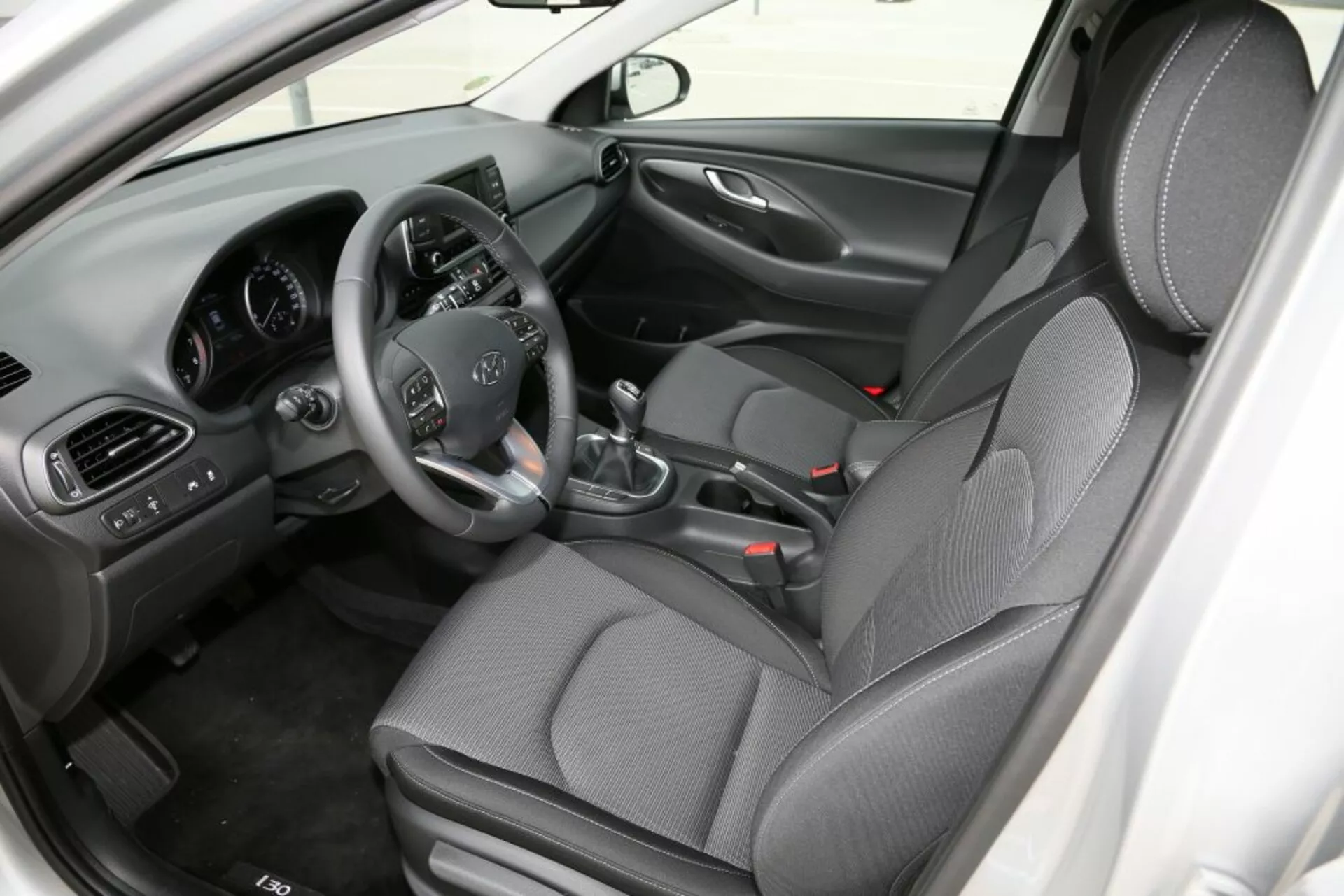 Interiörvy av Hyundai i30 2017 (i30-N) med fokus på främre kabinen, visar förarsätet med rattkontroller, manuell växelspak, central konsol och säten i mönstrad tyg