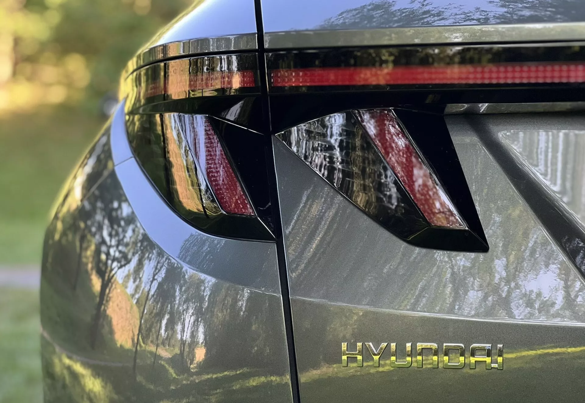 Närbild av bakdelen på Hyundai Tucson 2020, som visar vinklade LED bakljus, HYUNDAI branding, integrerad bakspoiler med bromsljus, och glansig metallisk yta