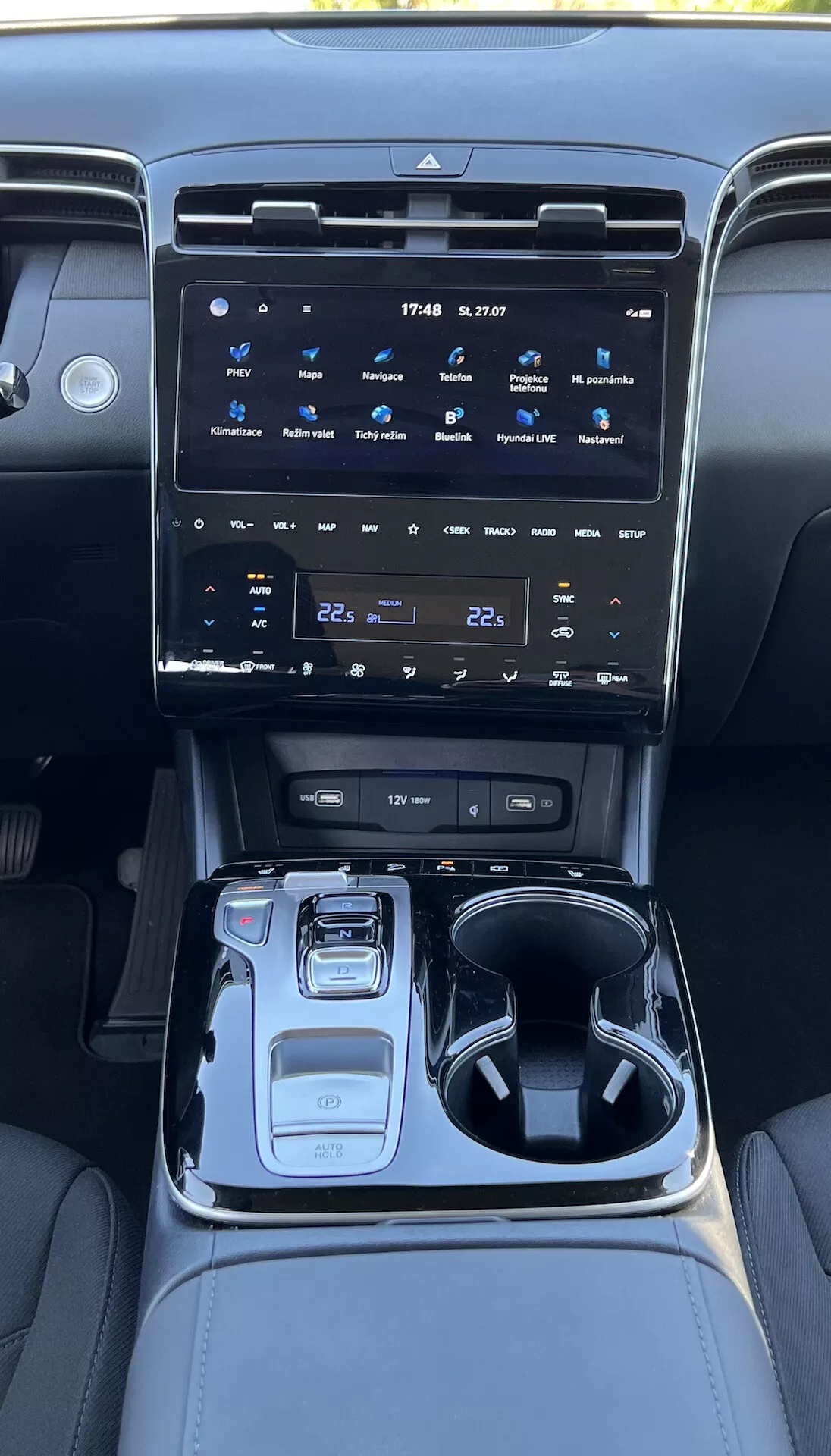 2020 Hyundai Tucson interiör som visar mittkonsolen med ett stort pekskärms infotainmentsystem, klimatkontrollknappar, elektronisk växelväljare, körningsläges väljare, mugg hållare, förvaringsutrymme och stämningsbelysning.
