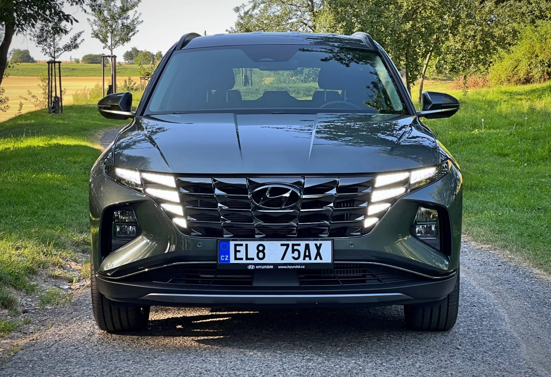 Hyundai Tucson 2020 sedd från ett frontalt lågt vinkel, som visar dess moderna design med skarpa, vinklade linjer, LED strålkastare, kaskadgrill och avancerade förarassistanssystem i en ljus daglig lantlig miljö