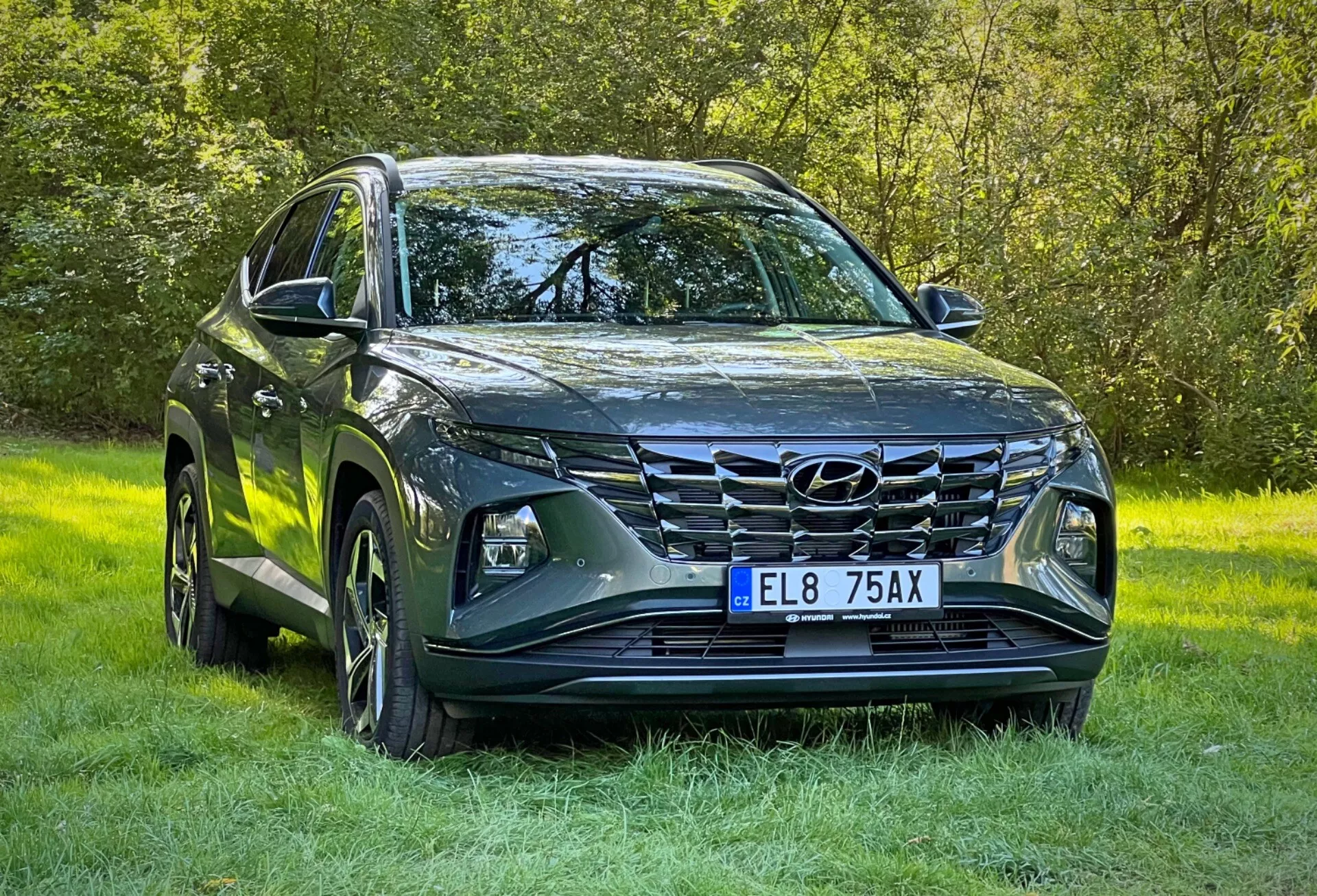 2020 Hyundai Tucson SUV i metallisk finish, visar LED-strålkastare, framträdande frontgrill, skulpterad motorhuvdesign, legeringshjul och sidospeglar med integrerade blinkers, parkerad på gräs vilket framhäver dess terrängkapacitet