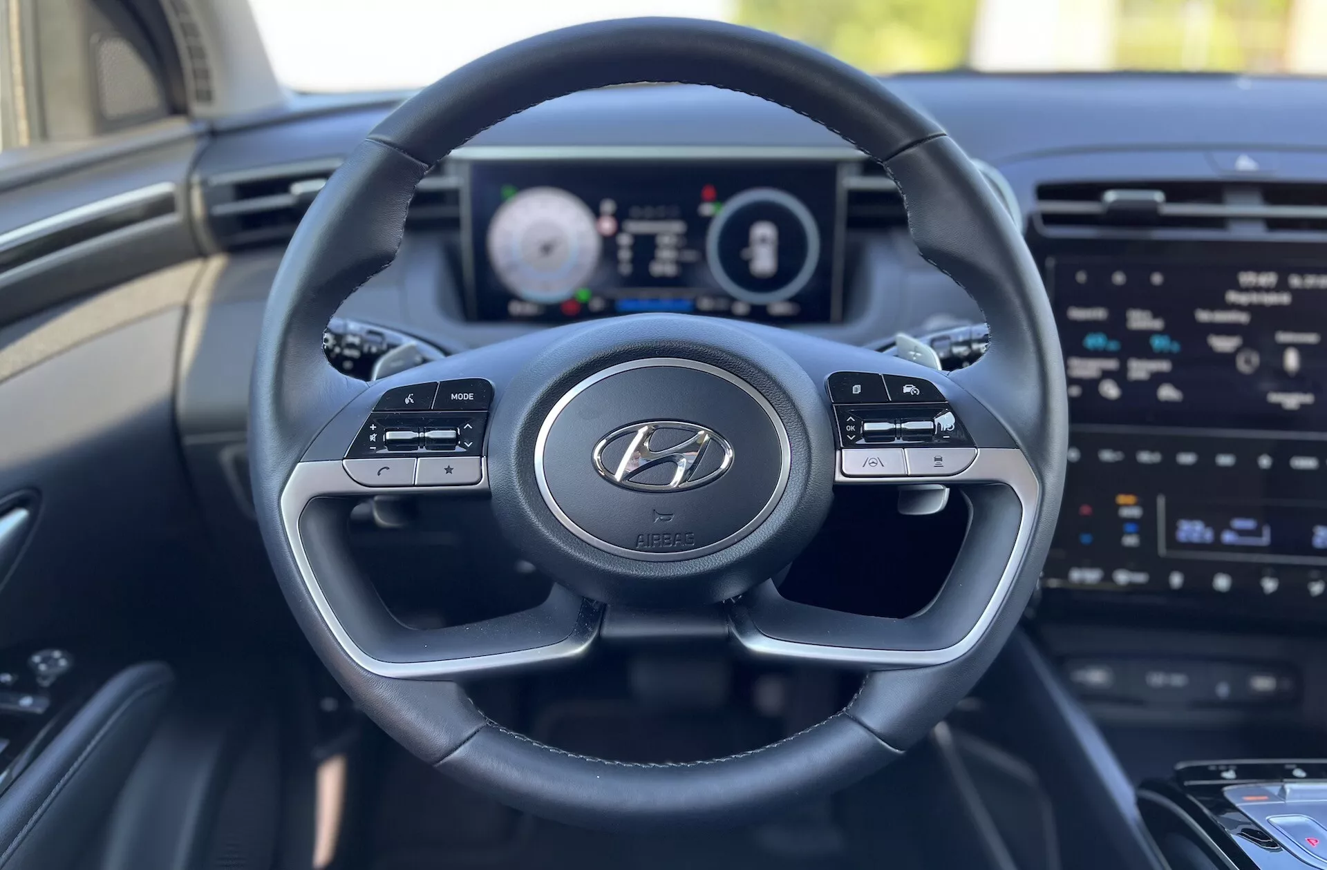 Interiörvy av Hyundai Tucson 2020 från förarsätets perspektiv som visar ratten med Hyundai-logotypen, digital instrumentpanel och infotainmentskärm