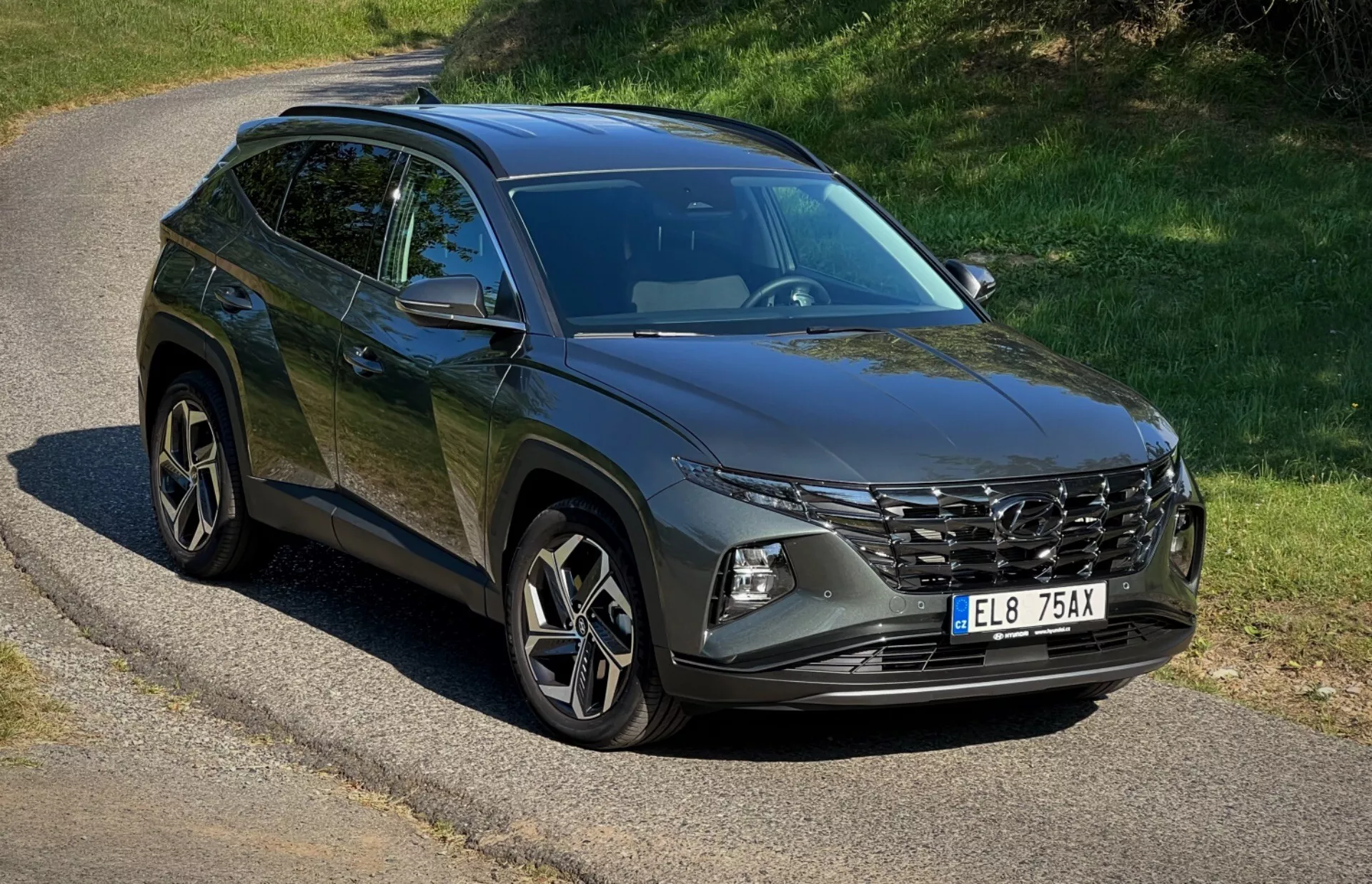 SUV Hyundai Tucson 2020 parkerad på en avskild väg som visar dess frontgrill, LED-strålkastare, legeringshjul och karosslinjer under naturligt solljus