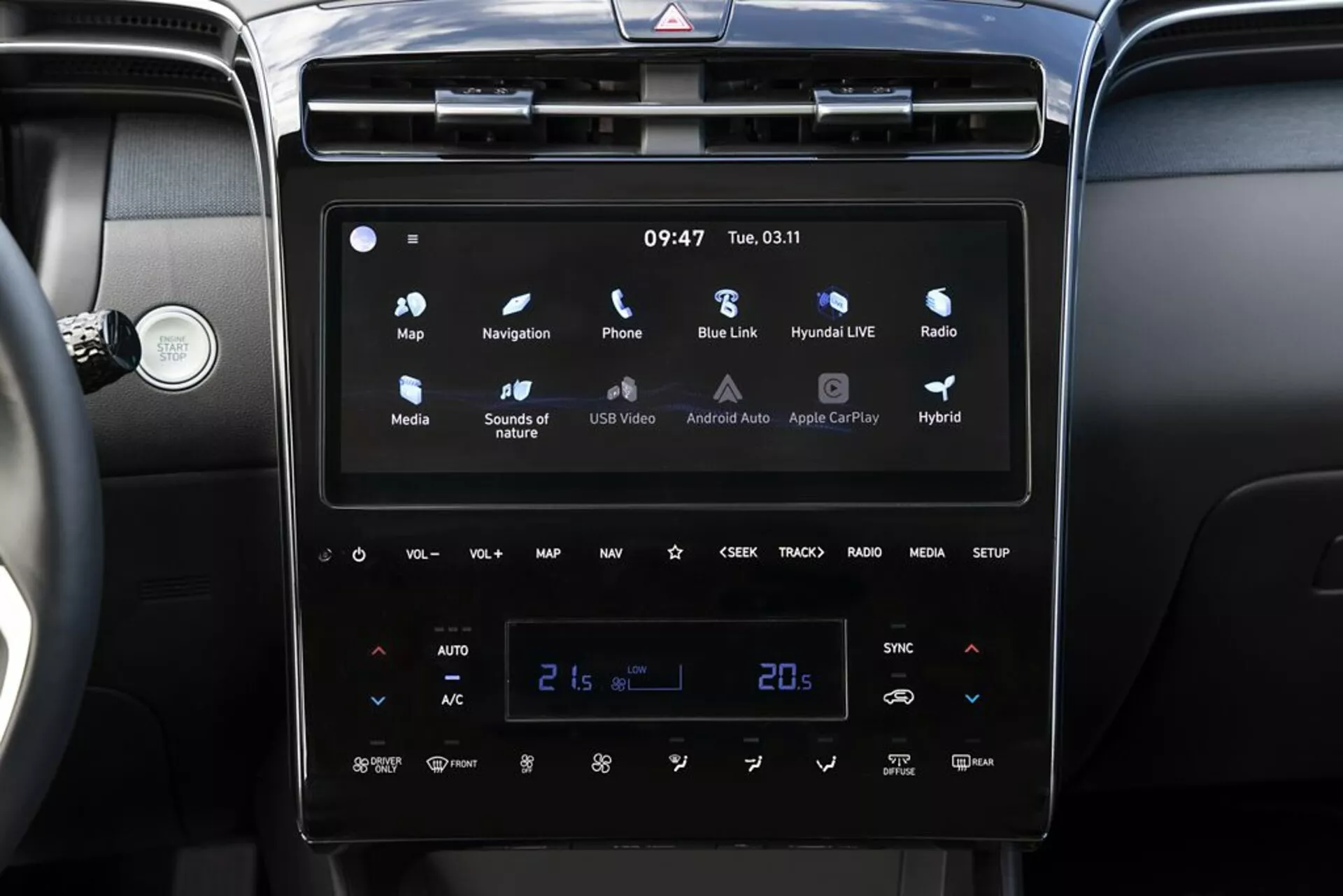 Interiör av Hyundai Tucson 2020 med ett modernt pekskärmsinfotainmentsystem med Android Auto och Apple CarPlay, dubbelzons automatisk klimatkontroll inställd på 21 grader Celsius och indikatorer för hybridfordon