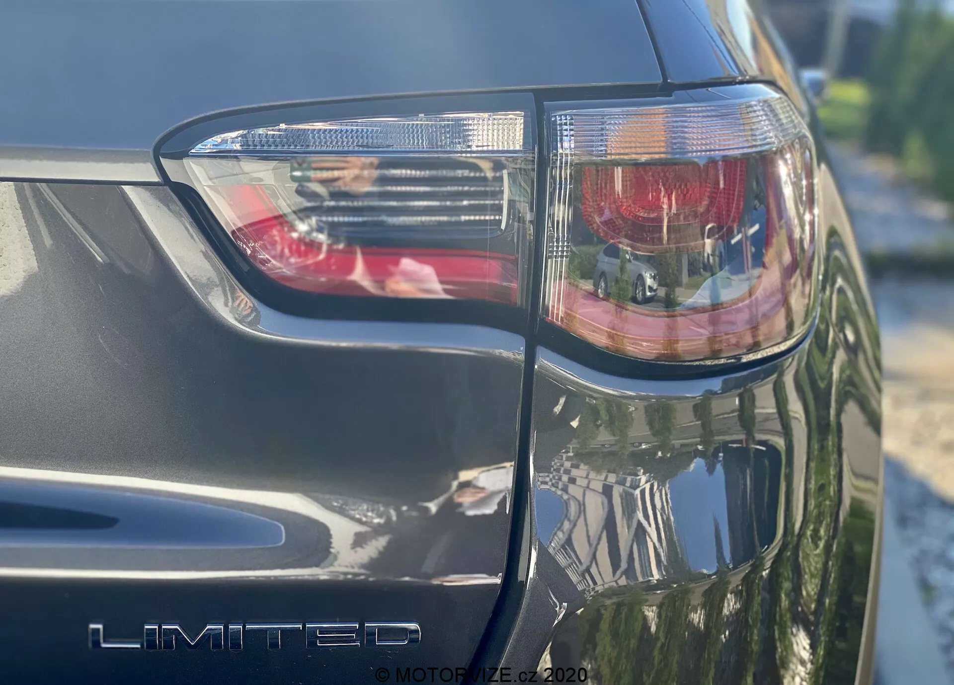 En närbild i vinkel på den bakre vänstra sidan av en Jeep Compass 2017, som visar baklyktorna med rött bromsljus och genomskinliga sektioner, tydligt visande 'LIMITED' trimemblemet. Den metalliska finishen och de skarpa vinklarna i designen med LED-belysningsteknik syns, tagen på en solig dag.