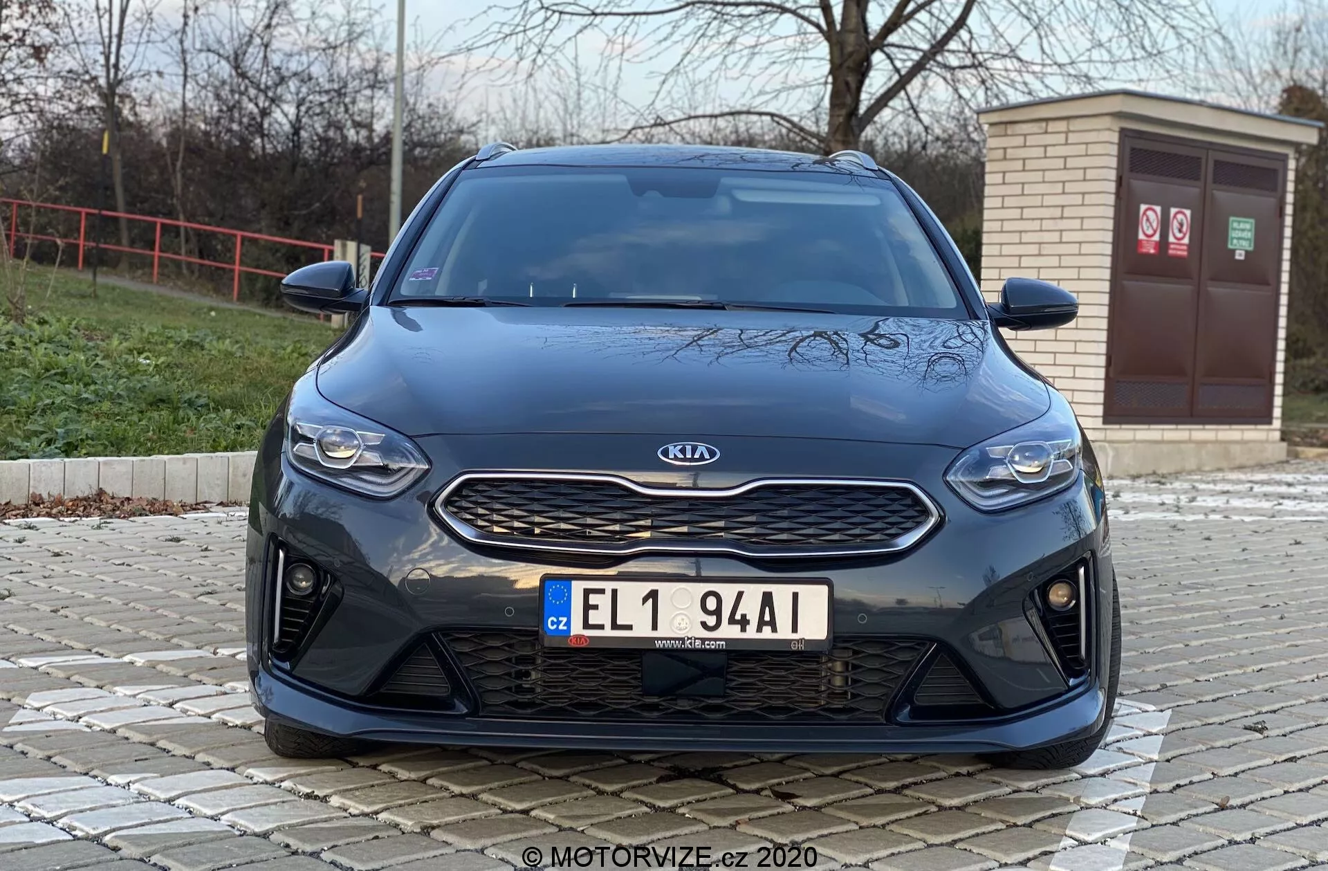 Frontal vy av en Kia Ceed 2018-bil från en låg vinkel, som visar frontala drag som grill, strålkastare och stötfångare med en modern estetik. Bilden lyfter fram den silvriga Kia-emblemet på en texturerad svart grill, eleganta horisontella strålkastare och en främre stötfångare med stora luftintag, vilket tyder på sportiga prestandafunktioner eller avancerad luftflödeskylning.