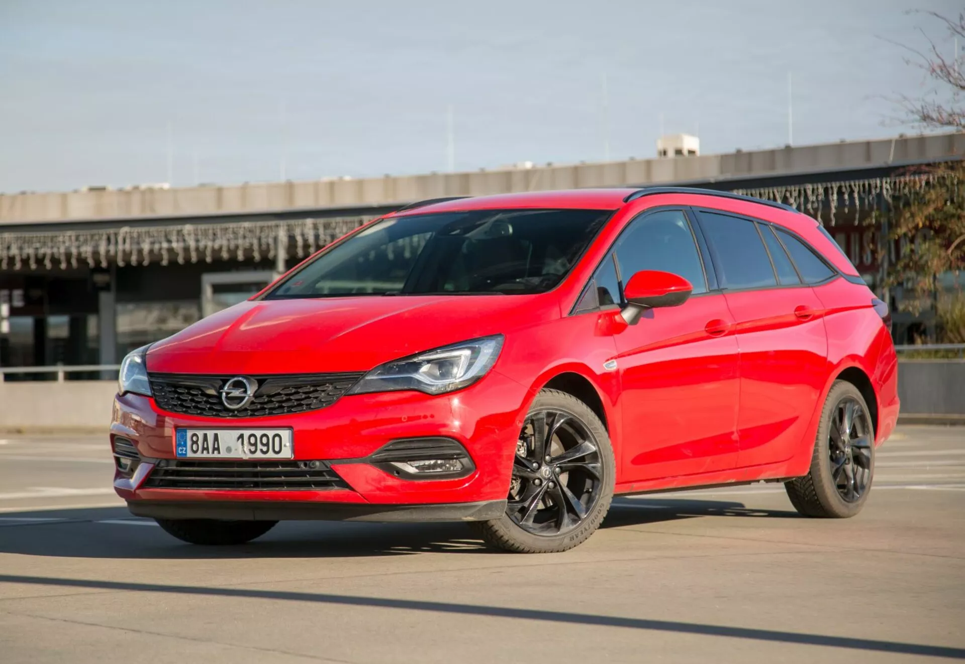 Ljusröd 2009 Kia Ceed hatchback parkerad på slät betong under klar himmel, visar LED strålkastare, snygg grill, mörka legeringshjul och modern aerodynamisk design från en trekvarts främre vinkel under dagtid.