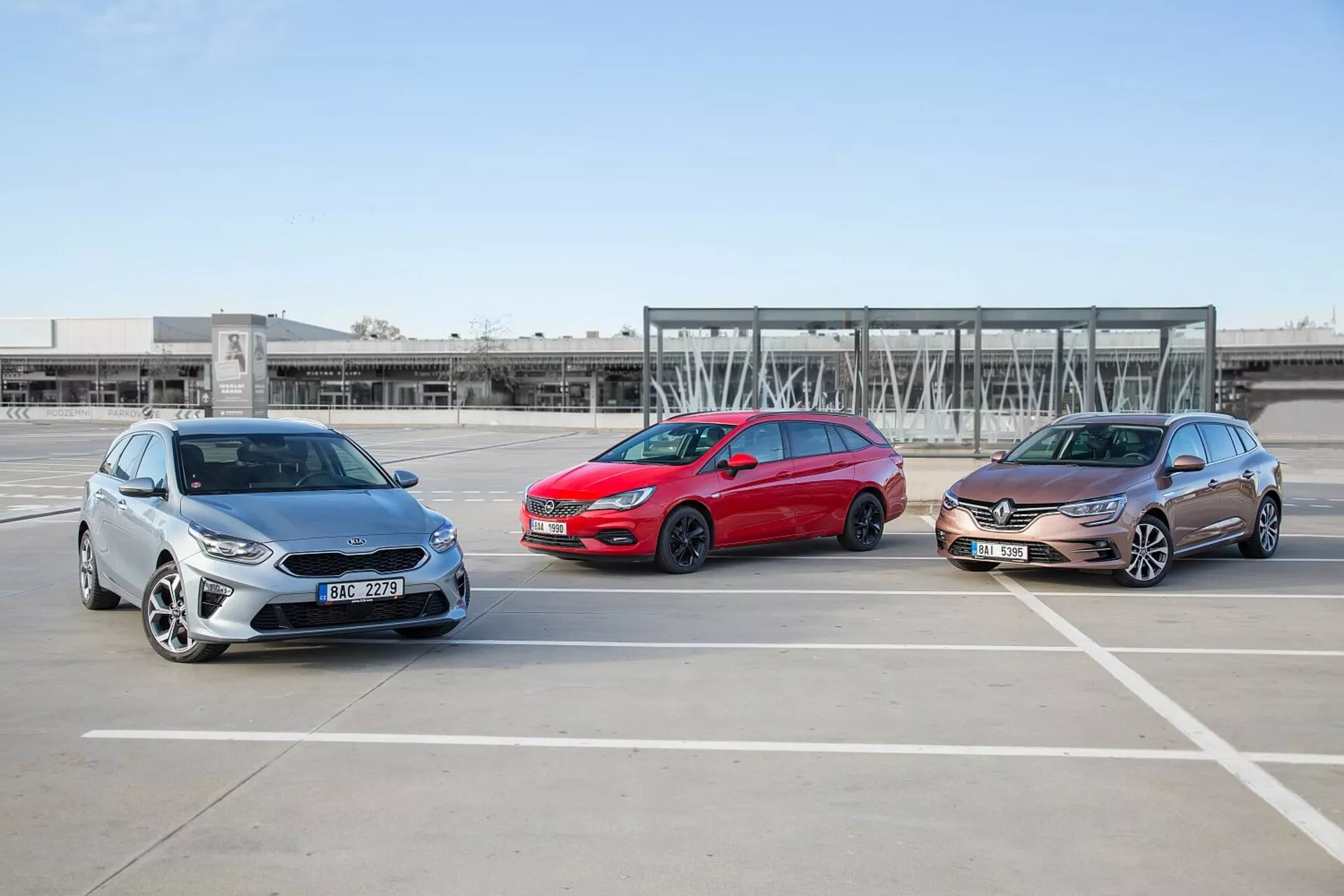 Tre Kia Ceed 2009 modeller, staggade i formation på en tom parkeringsplats, som visar sina fram- och sidoprofiler under klara väderförhållanden