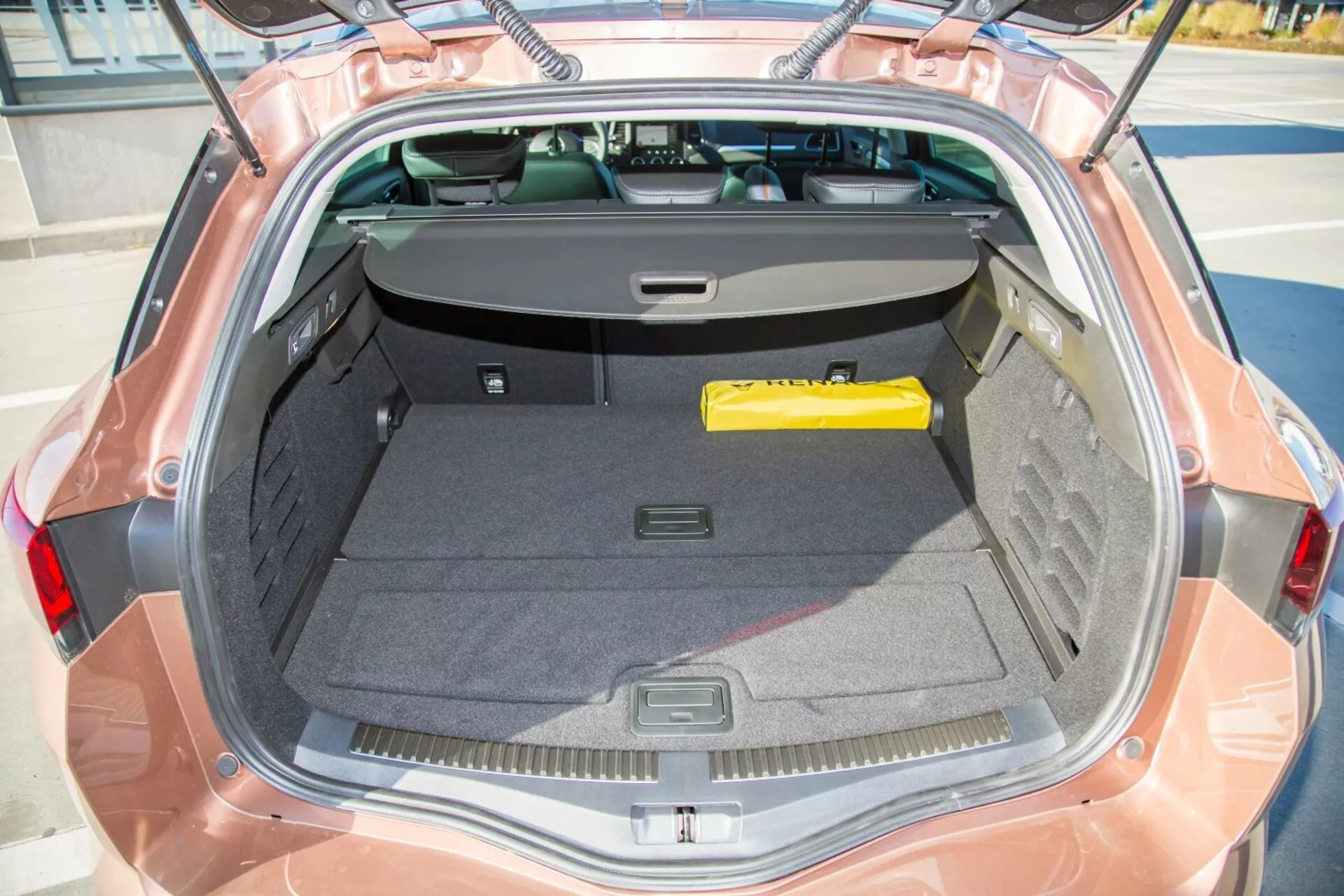 Närbild på bagageutrymmet i en Kia cee'd från 2009 från ett översiktsperspektiv som visar interiören, det öppna locket och delvis bakrutan med ett indragbart lastskydd, vilket framhäver rymlighet och förvaringsfunktioner.
