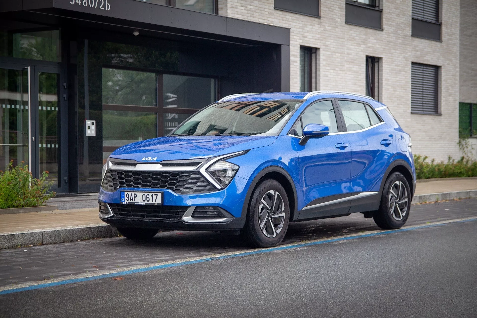 Kia Sportage 2022 i blått, med tre fjärdedels framsida på en stads gata, framhäver dess höga åktur, LED-strålkastare, legeringshjul och modern säkerhetsteknologi.