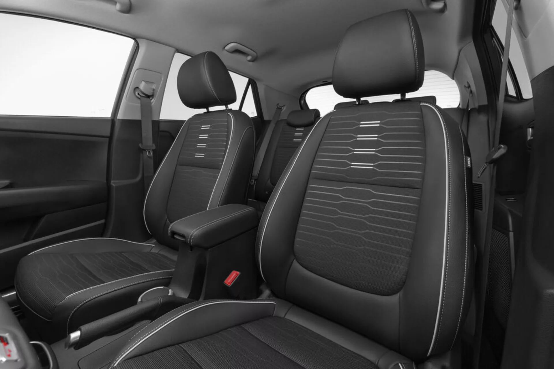 Högvinklad vy av Kia Stonic 2017:s främre interiör som visar svarta läderimitationssäten med horisontella sömmar, mittkonsol och röda säkerhetsbälteslåspunkter med fokus på design och layout