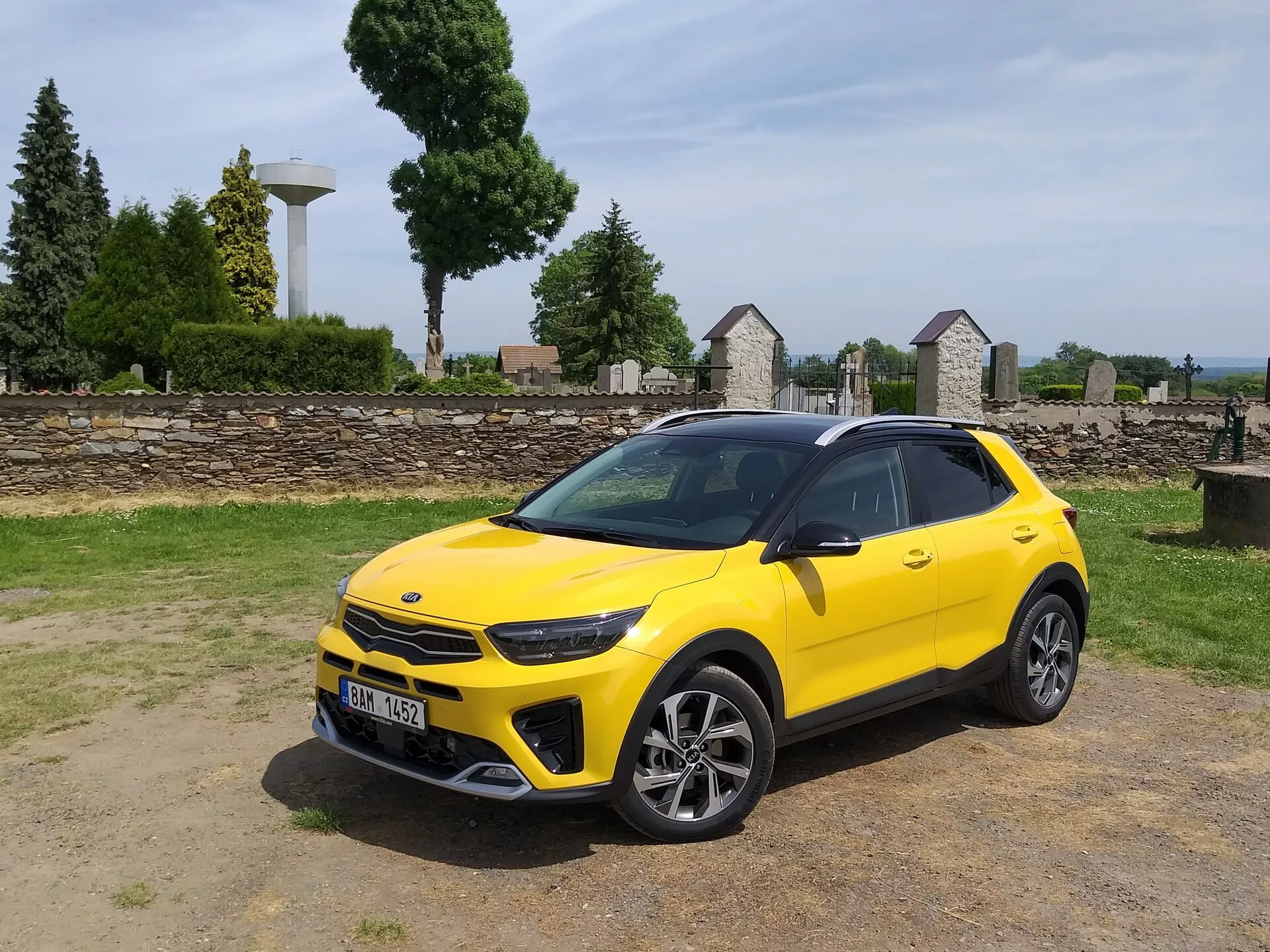 Kia Stonic 2017 i ljusgul färg, visar dess främre grill, LED-strålkastare, sportig främre stötfångare och elegant sidosilhuett med flerspakiga lättmetallhjul och takräcken, vilket framhäver fordonets kompakta crossoverestetik och avancerade designegenskaper.