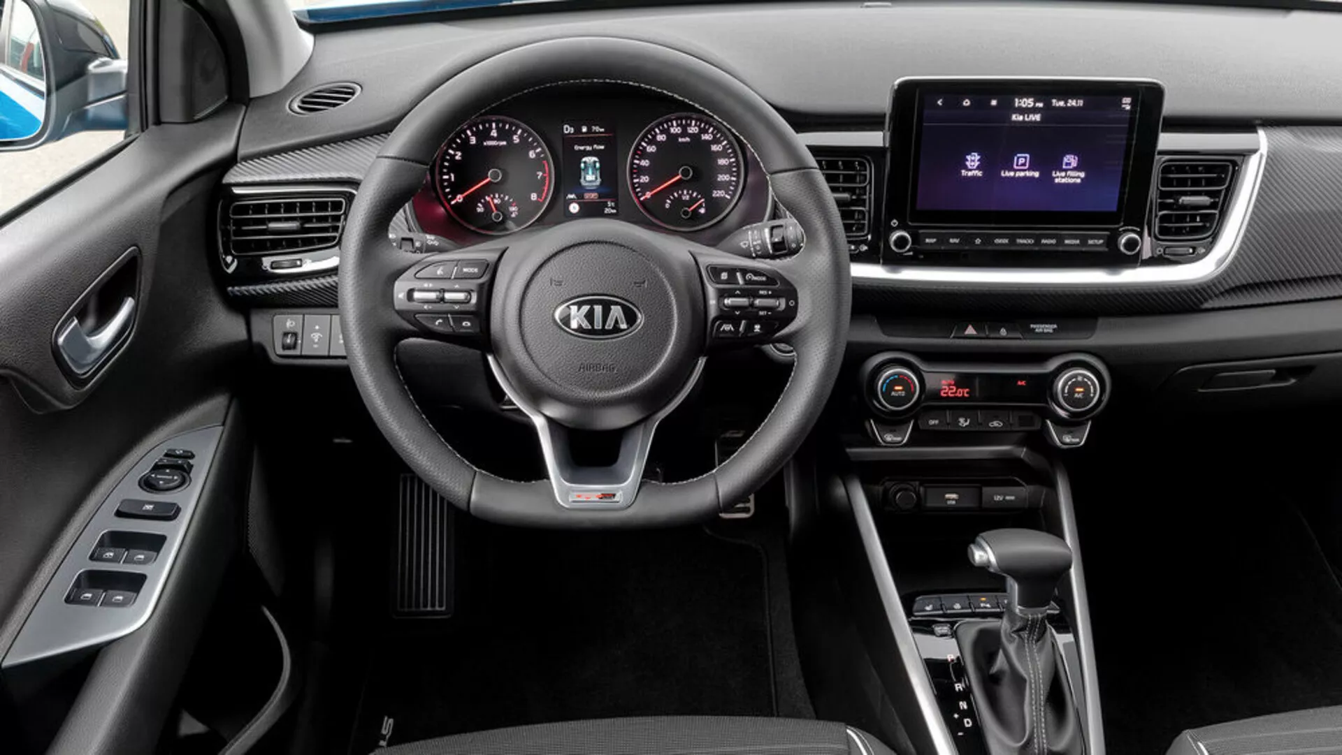 Interiörvy av en Kia Stonic 2017 från passagerarens perspektiv, med en trespakig ratt med monterade kontroller, analog-digital instrumentkluster, pekskärmsinfotainmentsystem, klimatkontroll, automatväxellåda och körmodväljare.