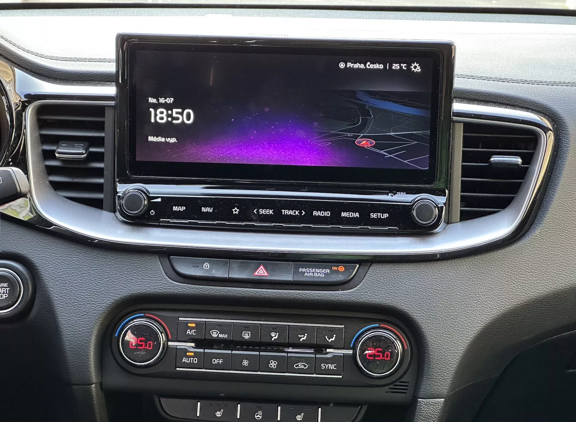 Detaljerad vy av Kia Xceed 2022:s interiör som visar mittkonsolen med en infotainment-pekskärm som visar ett färgrikt gränssnitt med navigering och medieinformation, en rad snabbåtkomstknappar, varningsljuskontroll och en panel för dubbelzons klimatkontroll, allt inramat med silverfärgad trim.
