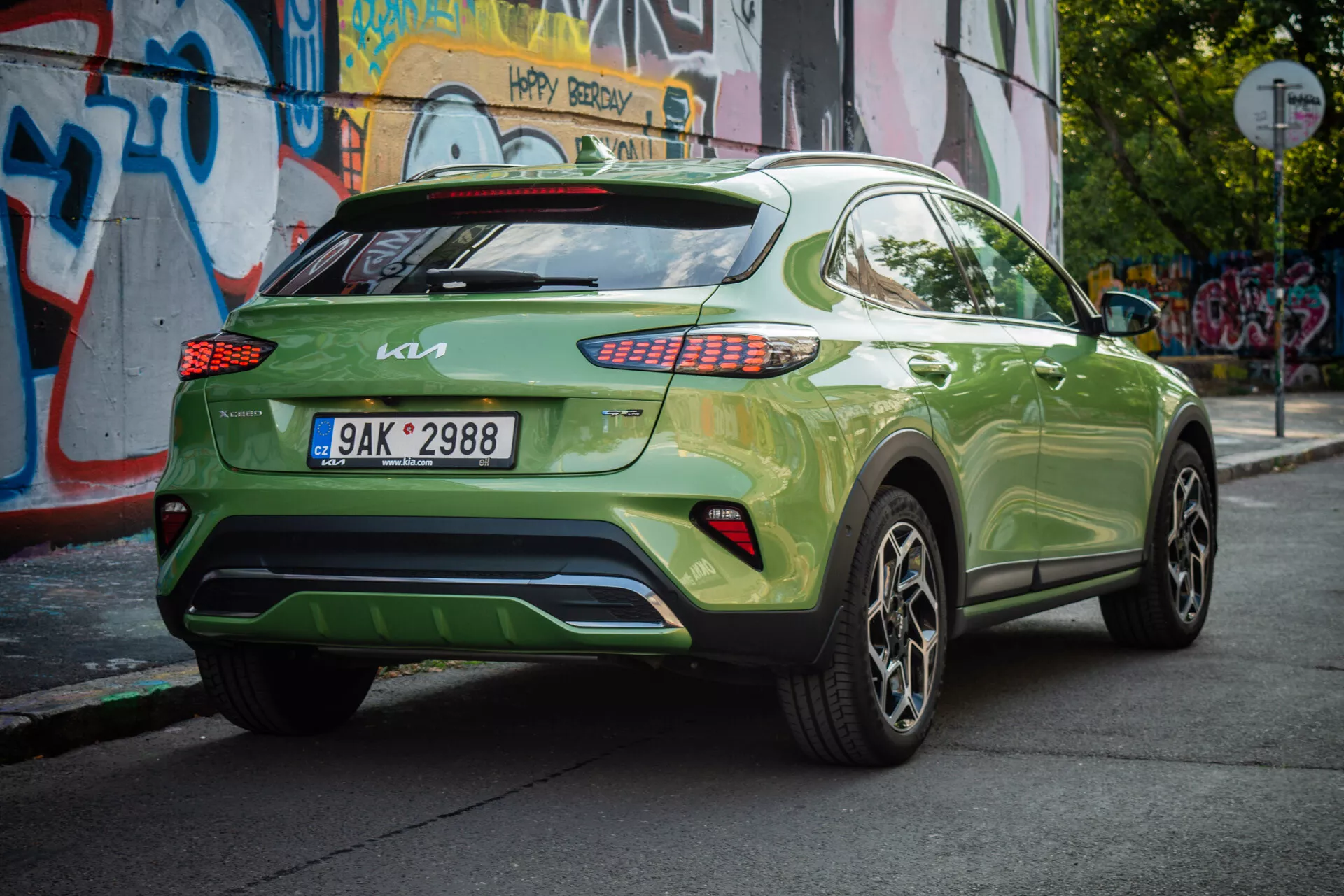 Kia XCeed 2022 i vibrerande grönt, visar sin trekvarts bakifrån vinkel med europeisk registreringsskylt, LED-baklampor, legeringshjul och urban bakgrund.