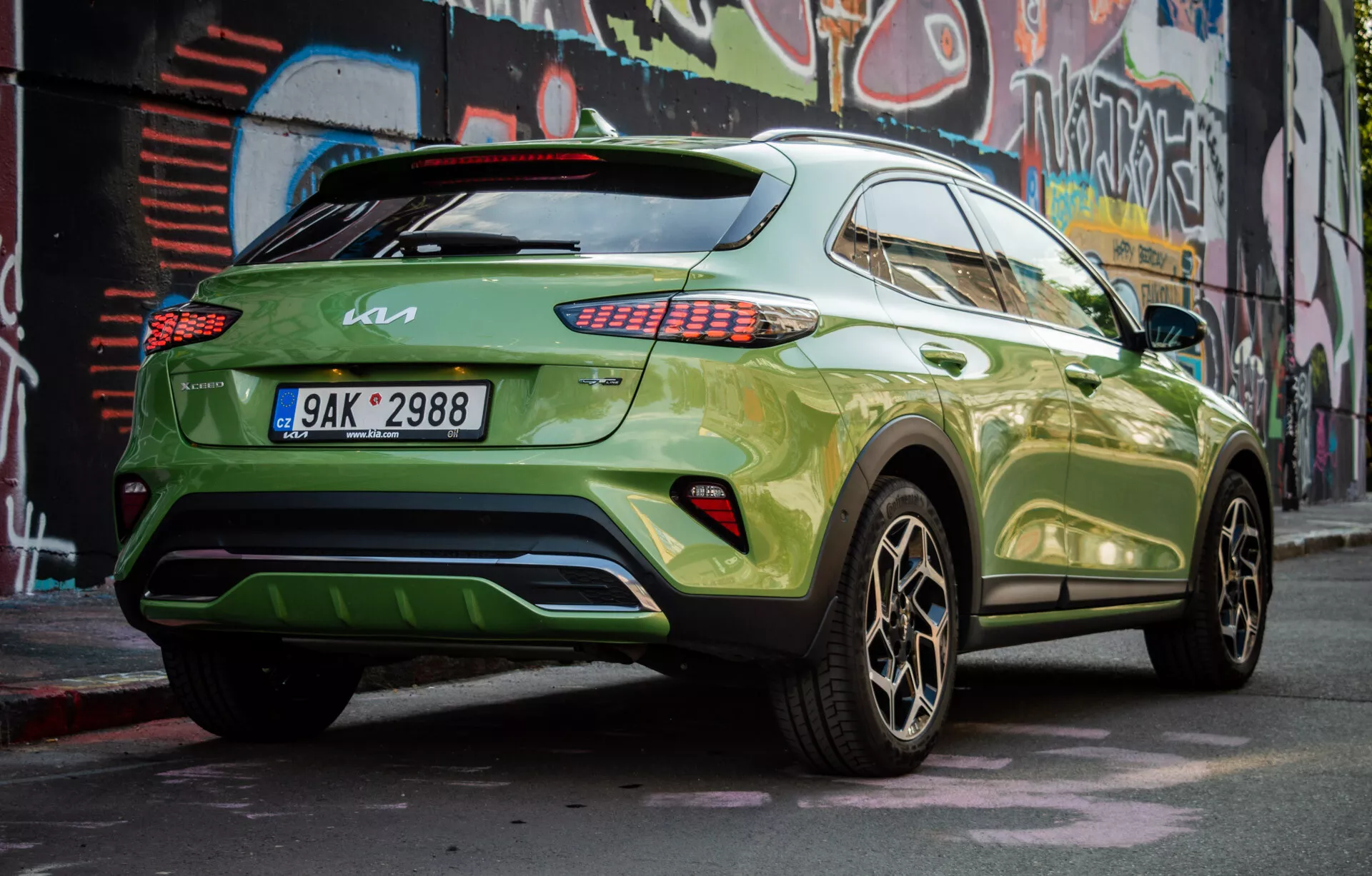 2022 Kia XCeed modern crossover SUV parkerad diagonalt som visar dess högra bakre del, med livlig grönt lack och mörka legeringshjul, demonstrerar fordonets sidosprofil, bakre design, LED-bakljus, tonade fönster, ett takspoiler och potentiell bakre diffusor