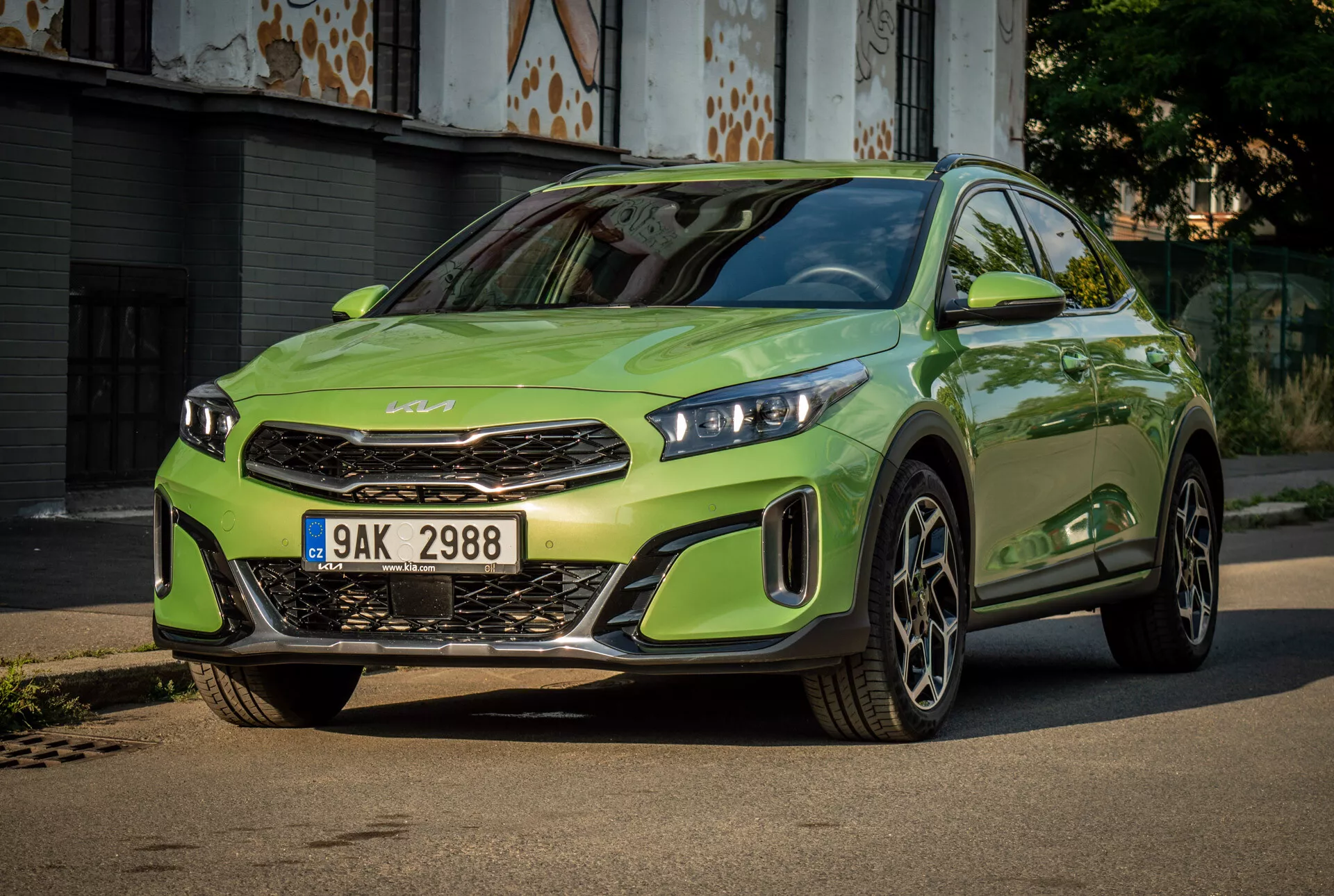 Kia XCeed 2022 i livligt limegrönt med LED-strålkastare, framträdande frontgrill med märkesemblem, sportig frontkofångare och stora legeringshjul, centrerad på en asfalterad väg med en urban bakgrund