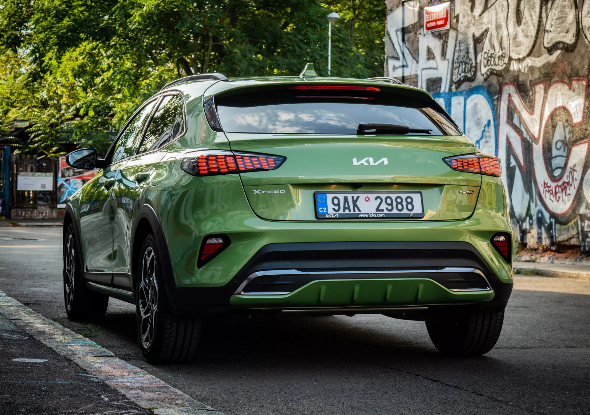 Bakvy av en grön 2022 Kia XCeed crossover/SUV som visar varumärkning, LED-baklysdessign, registreringsskyltplacering, lägre stötfångarens estetik och glansig finish på en stadsgata.