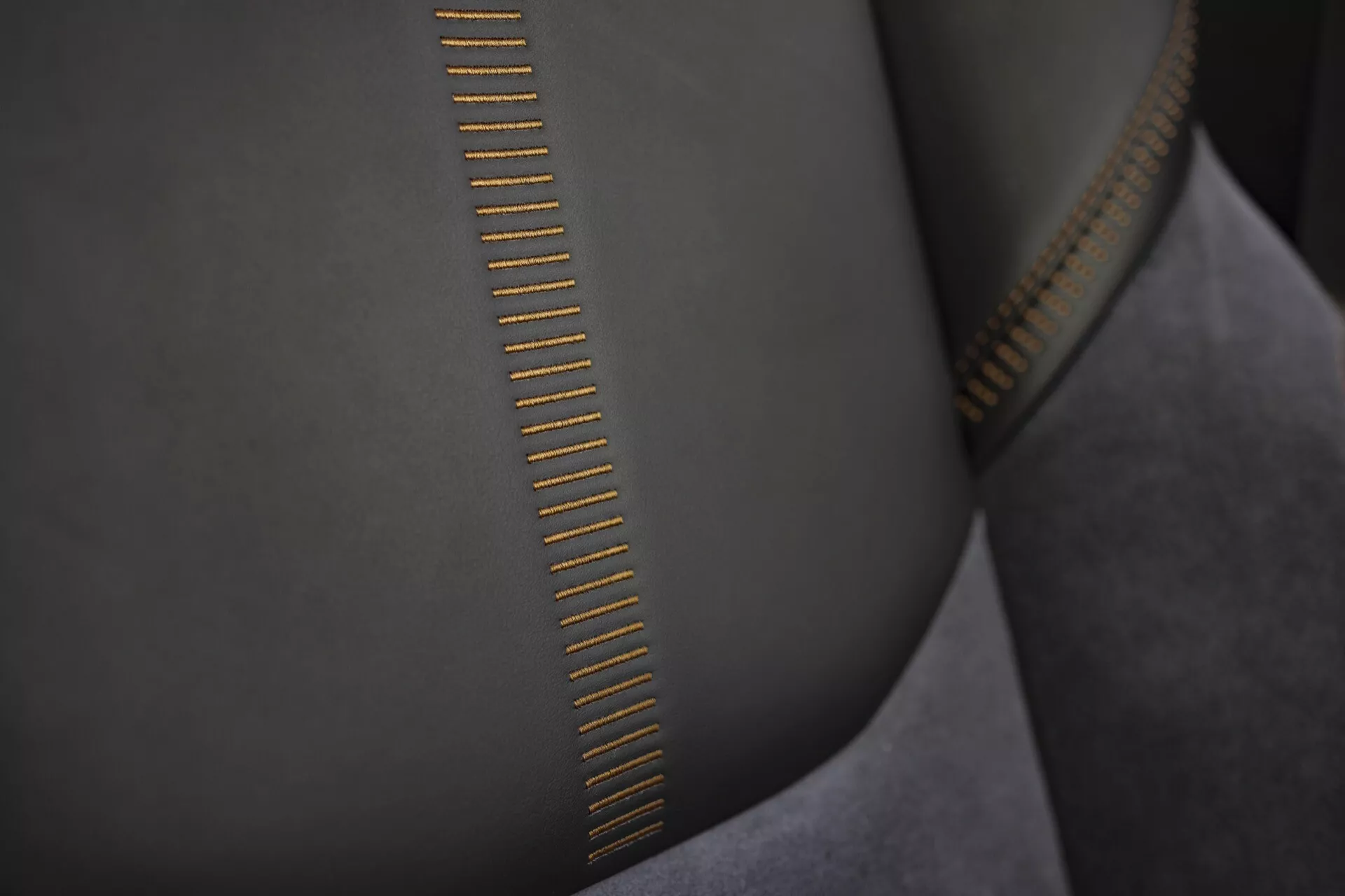 Närbild av högkvalitativa dragkedjetänder med detaljerad sömnad på slät, mockaliknande tyg och guldtonad metallisk finish som reflekterar ljuset