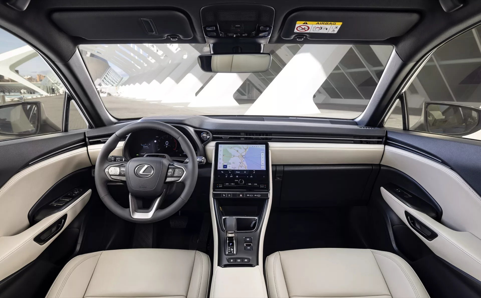 Framifrån-central vy av interiören i Lexus LBX 2024 med tvåtonsinstrumentbräda, multifunktionsratt med tre ekrar, stor infotainment-skärm med GPS och premium beige säten