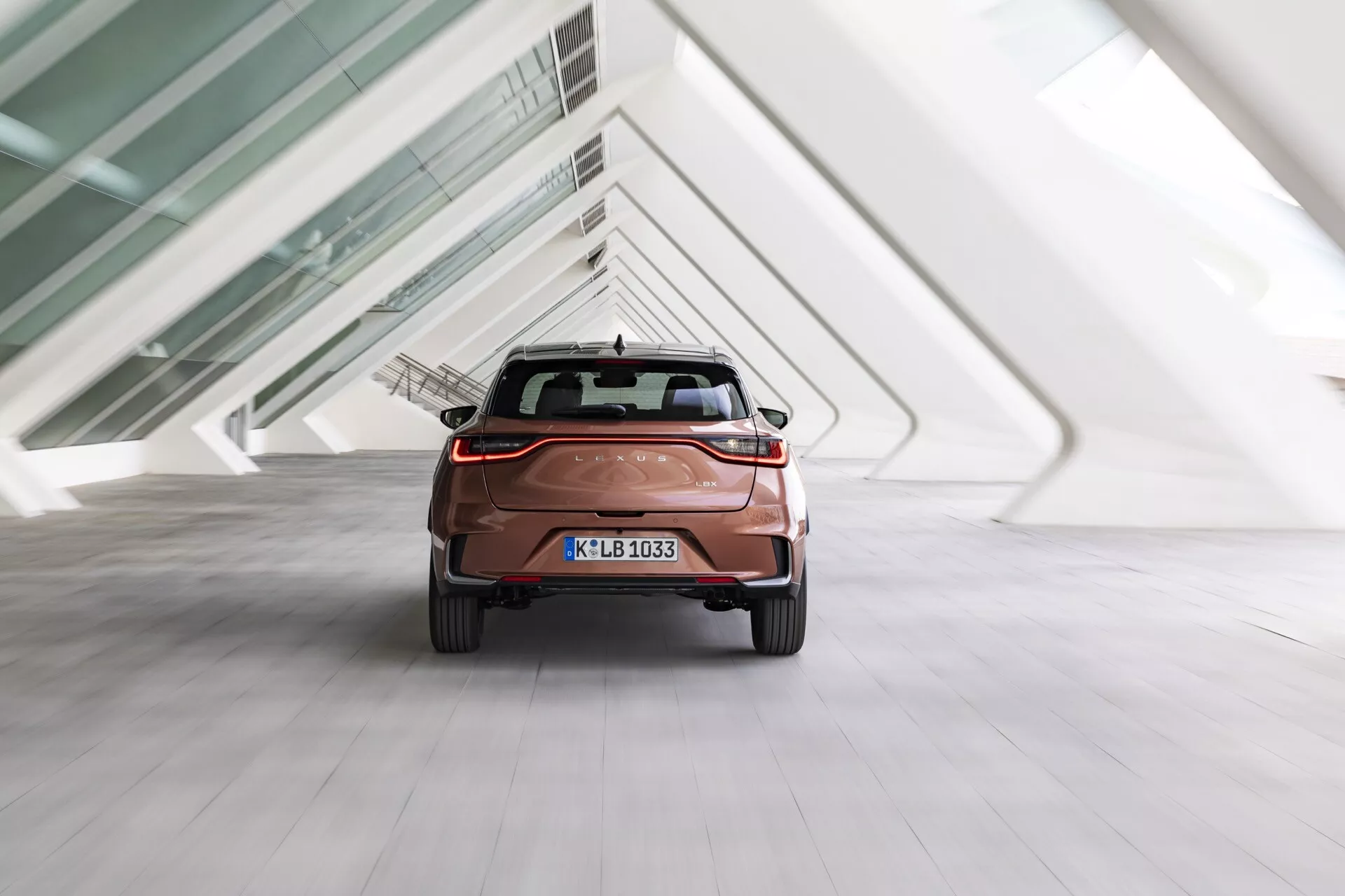 Lexus LBX 2024, 1:a generationen, sedd från bakre vinkel som visar baklyktor, bakre stötfångare och bagagelucka i inomhusmiljö