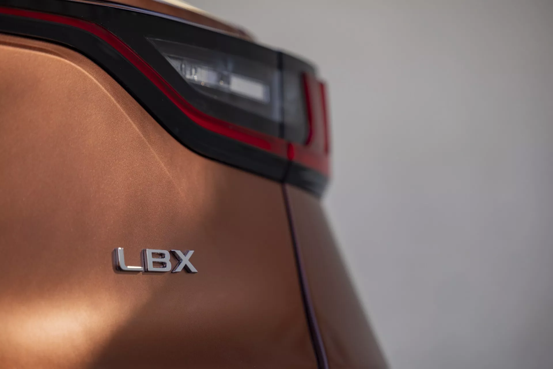 Närbild av Lexus LBX 2024s bakre del, visar detaljer av LED-baklykta och LBX-emblem med metallfinish och aerodynamisk design